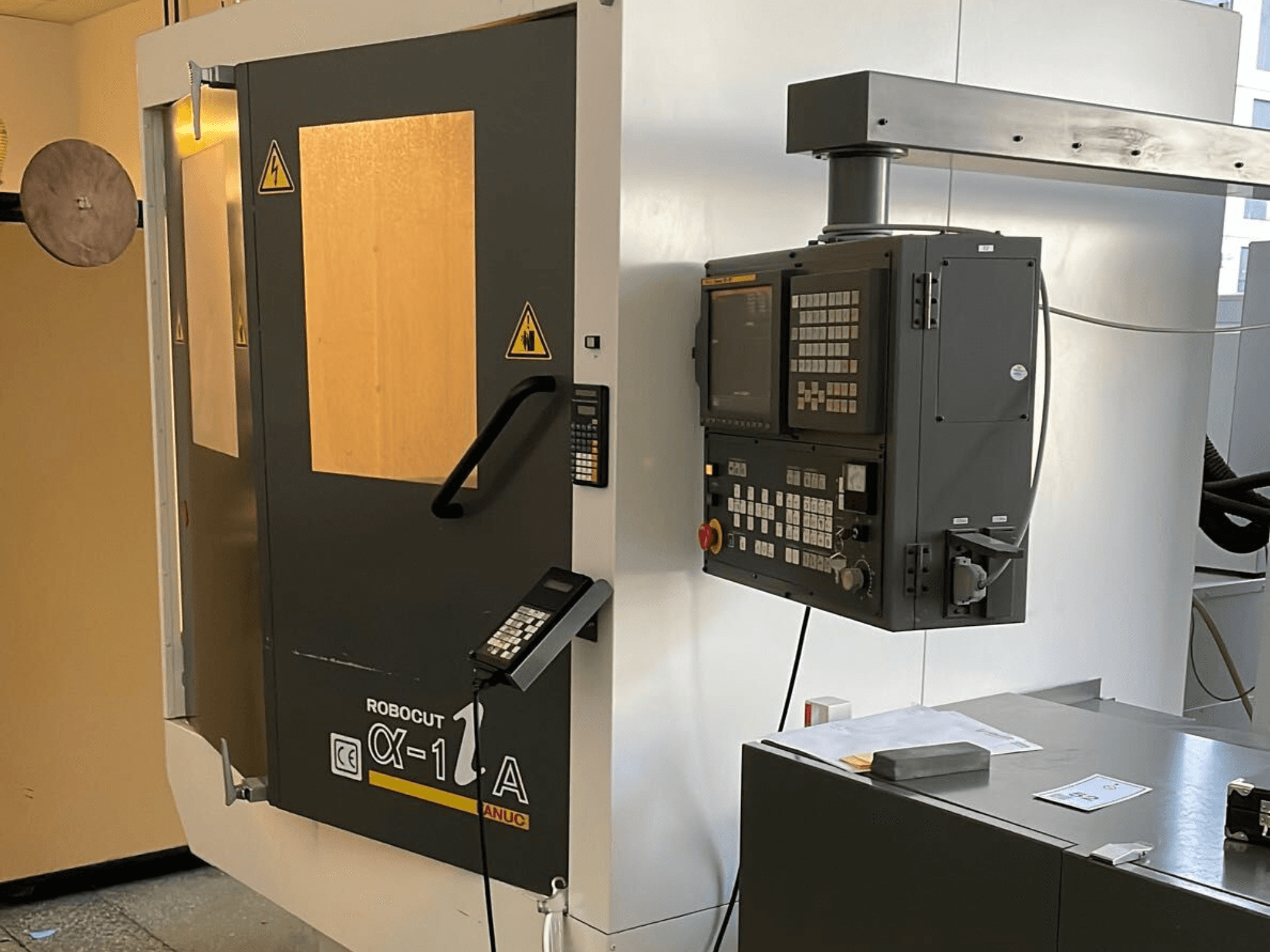 "Robocut CX-1 A" staklės su valdymo skydeliu; iš priekio matomos apsauginės durelės ir valdymo sąsaja.