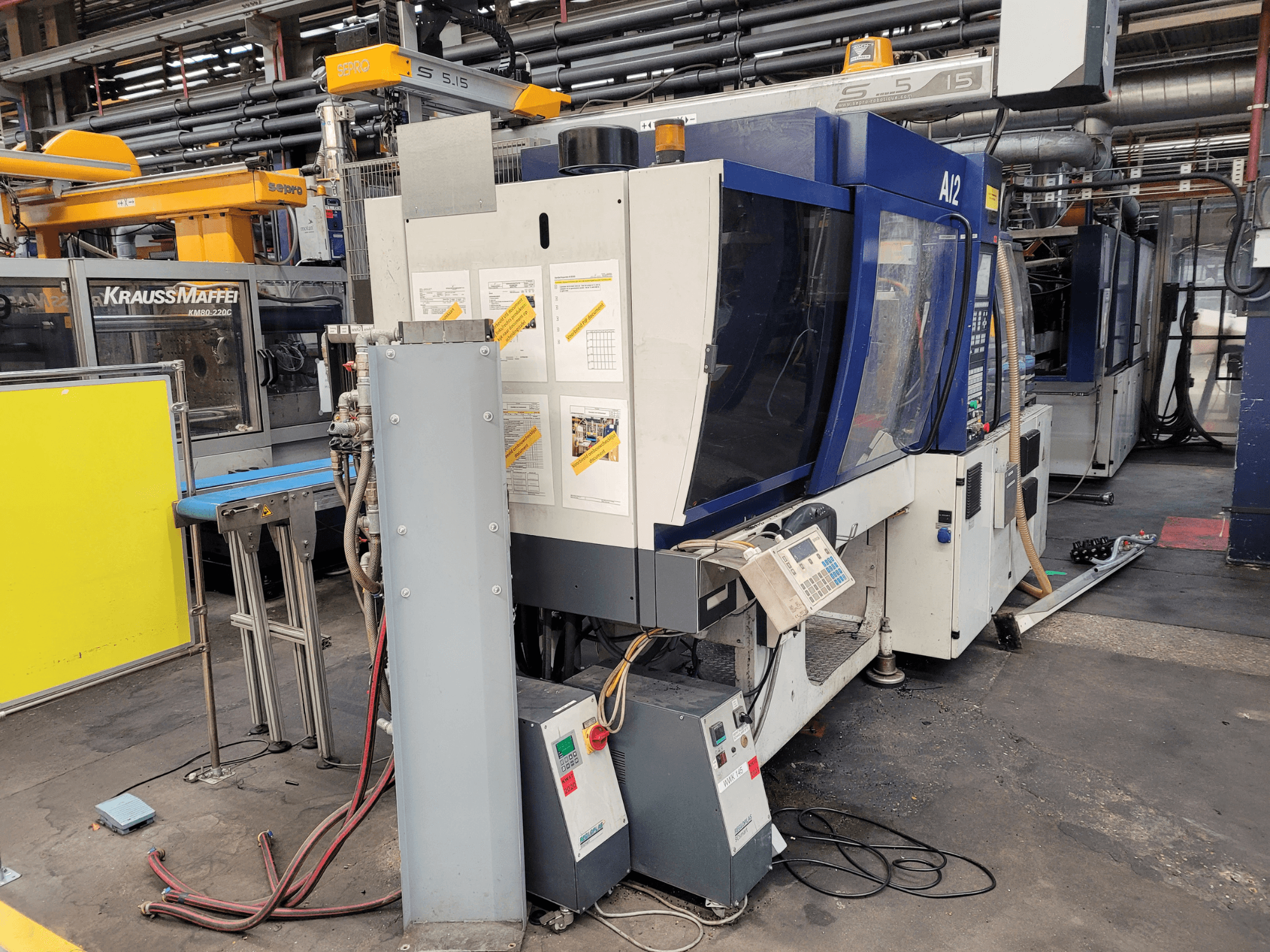 "KraussMaffei" liejimo mašinos KM80-232G modelio KM80-232G priekinis vaizdas su valdymo skydeliu ir darbiniais komponentais.