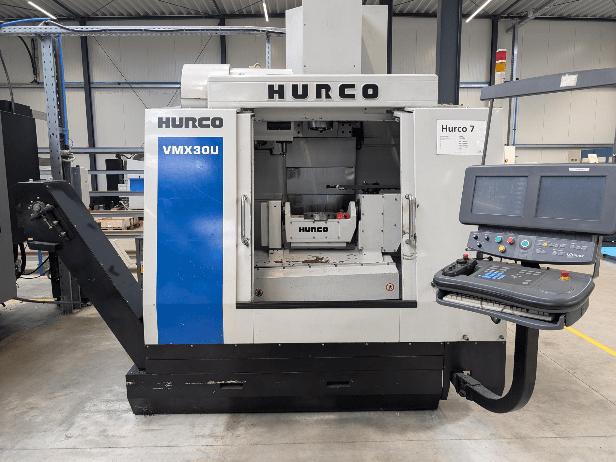 Hurco VMX30U CNC staklių vaizdas iš priekio su valdymo skydeliu; staklės turi erdvų vidų ir tikslią valdymo sąsają.