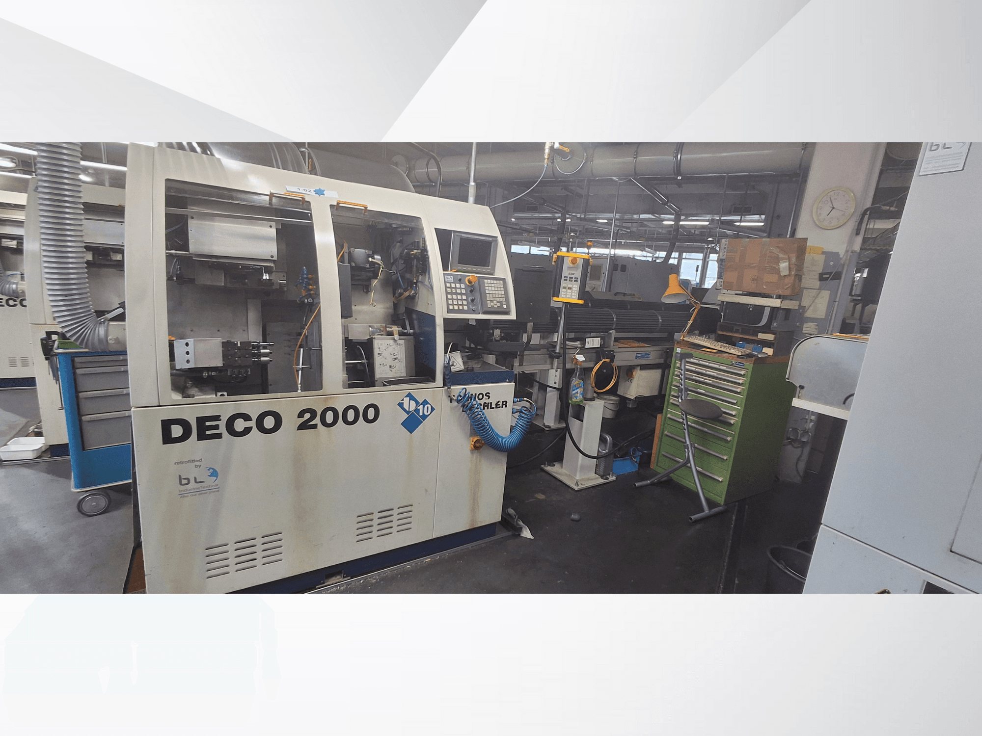DECO 2000 įrenginys iš priekio: valdymo skydelis, vamzdžiai ir netvarkinga darbo vieta su įrankiais ir dėžėmis.