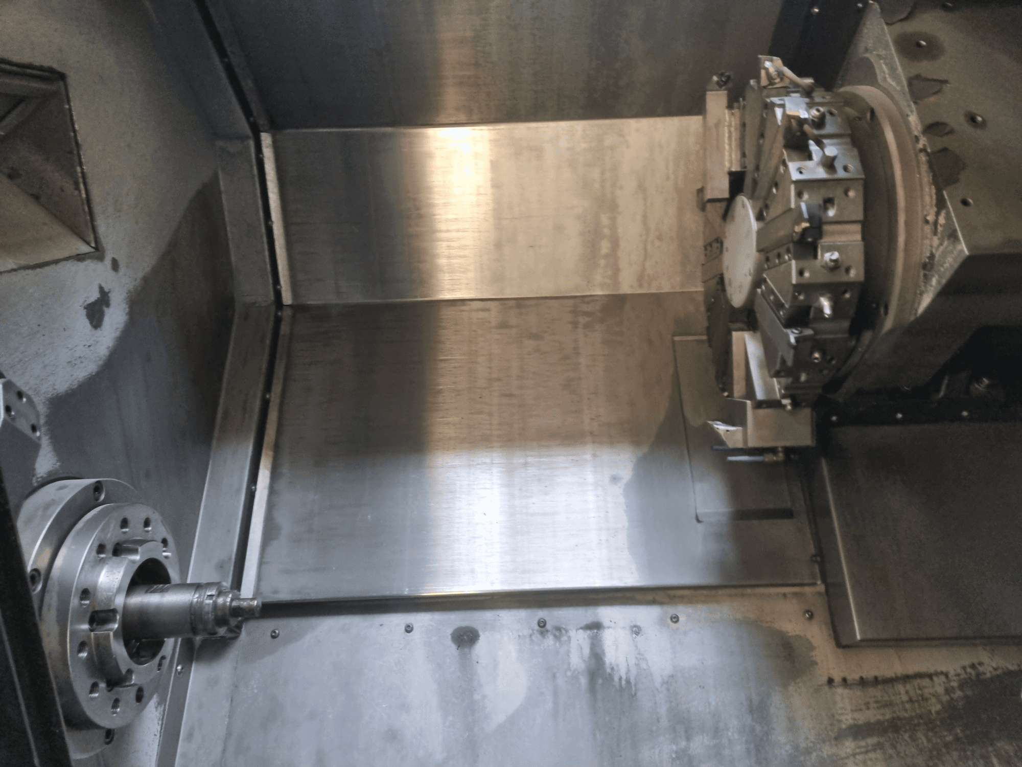 CNC staklių su besisukančiu sukliu ir metaliniu darbiniu paviršiumi interjero vaizdas, demonstruojantis pramoninę tiksliąją inžineriją.