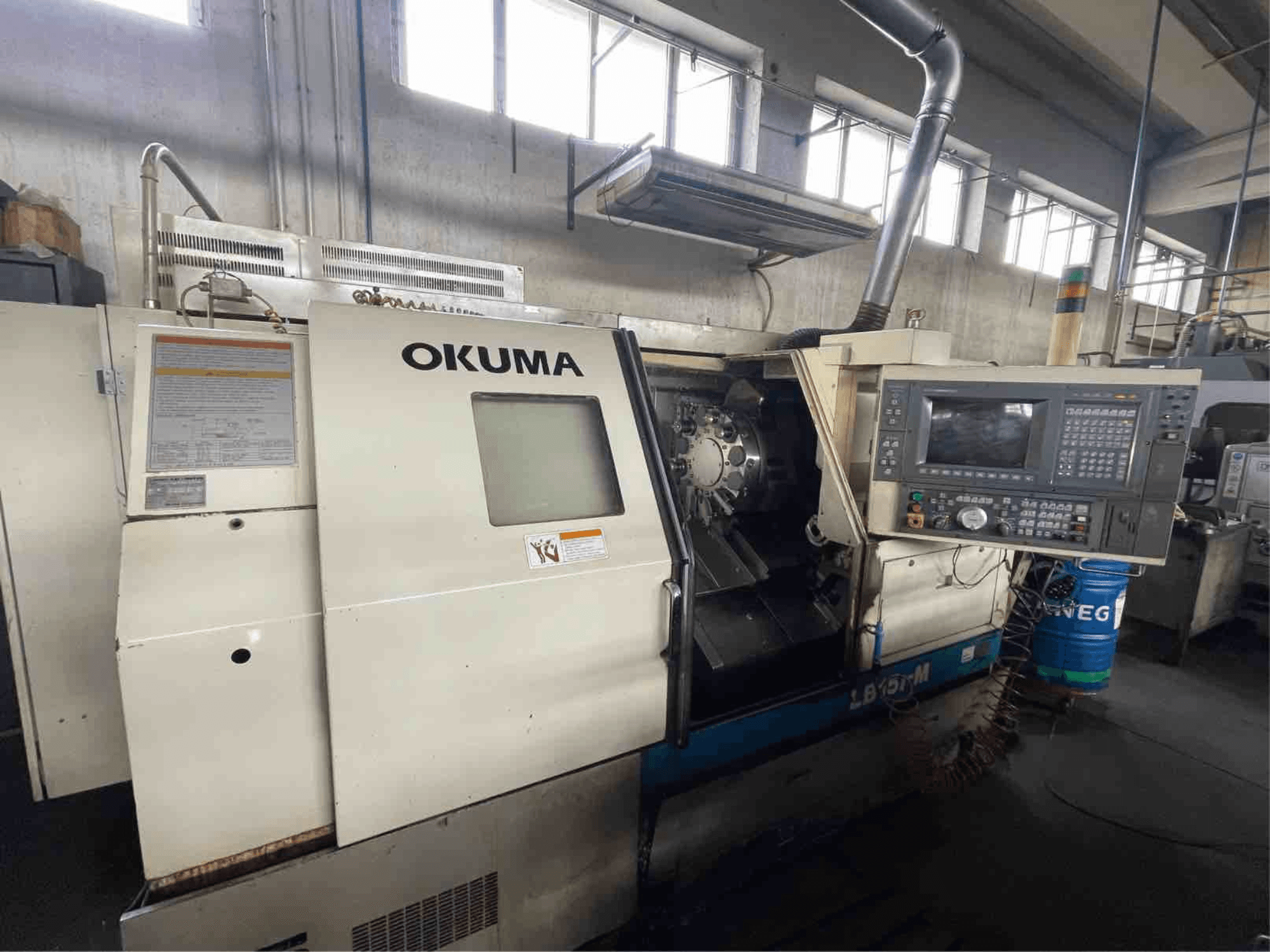 Okuma LB15i-M horizontalios tekinimo staklės, vaizdas iš priekio; valdymo skydelis ir pjovimo įrankių zona su išsamiais indikatoriais.
