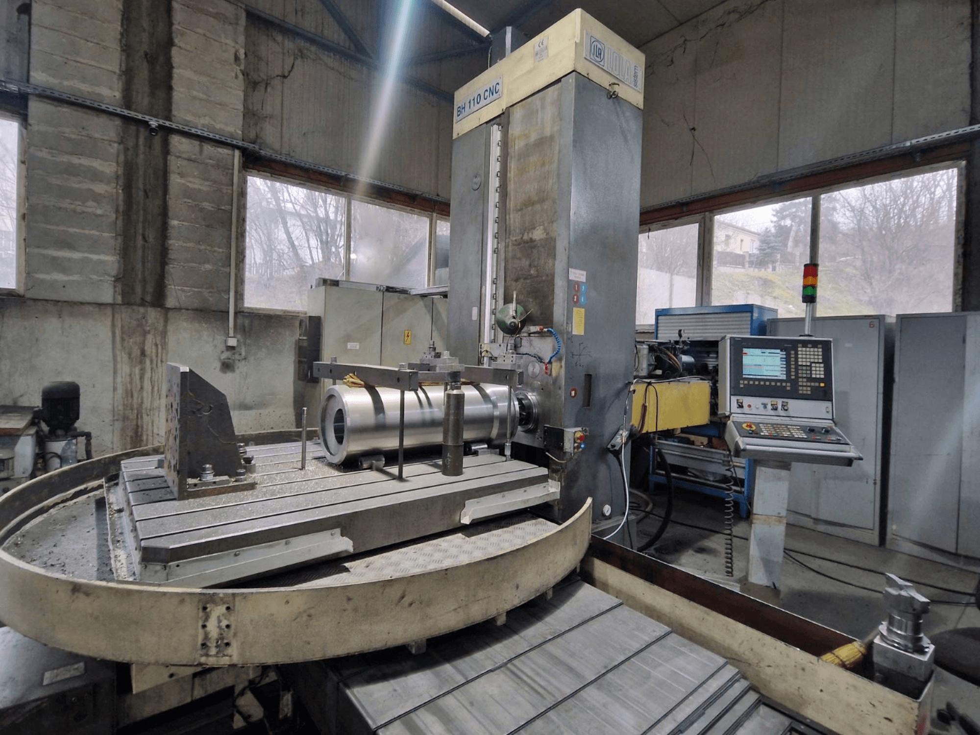 LOLA BH 110 CNC gręžimo staklės dirbtuvėse, vaizdas iš priekio, metalinis ruošinys ir valdymo pultas.