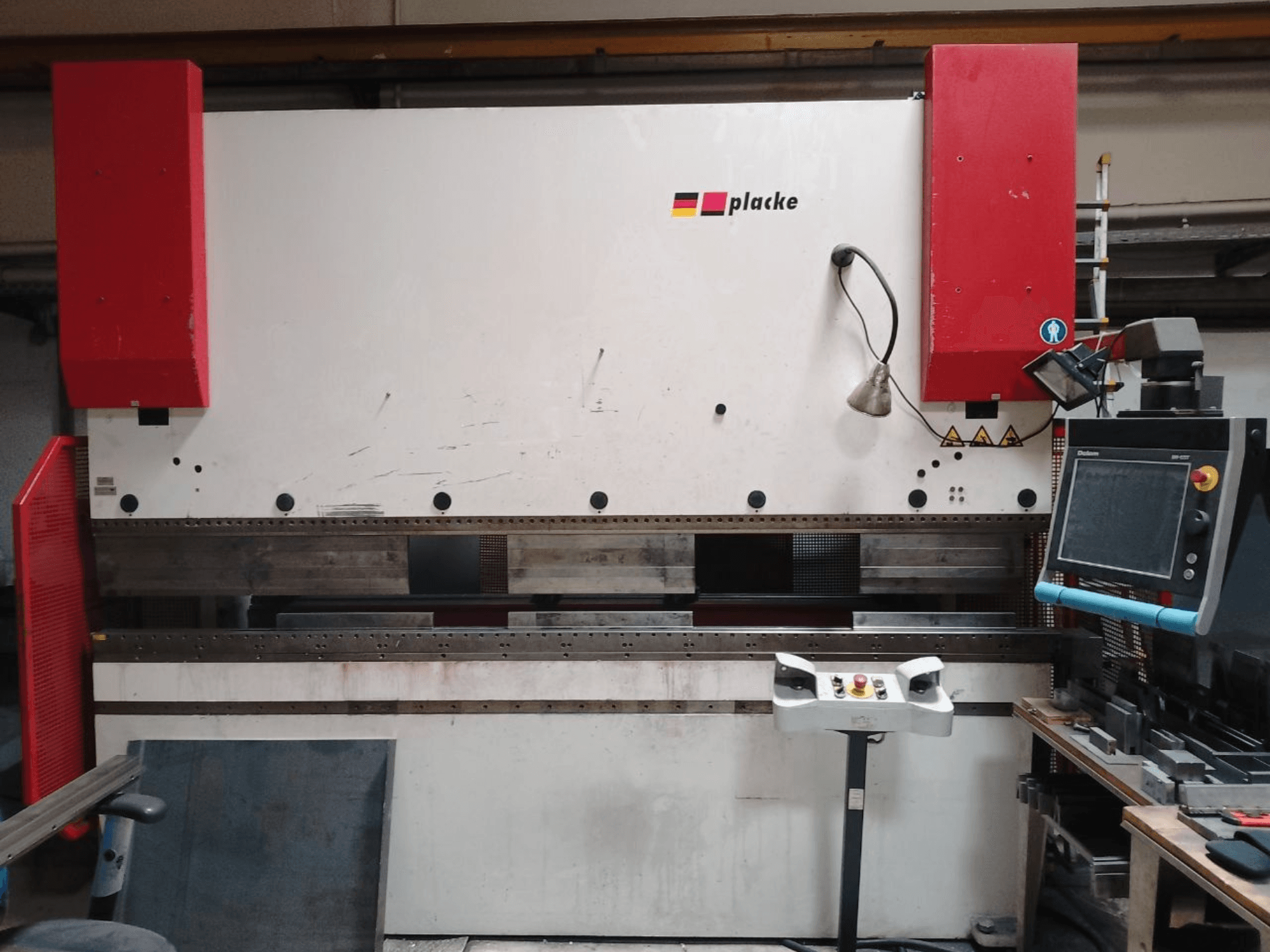 Lankstymo presas „PLACKE QPB-4 150/3100“, vaizdas iš priekio, kuriame matomas valdymo pultas, raudoni svirtiniai rankenėliai ir metalo lenkimo zona.