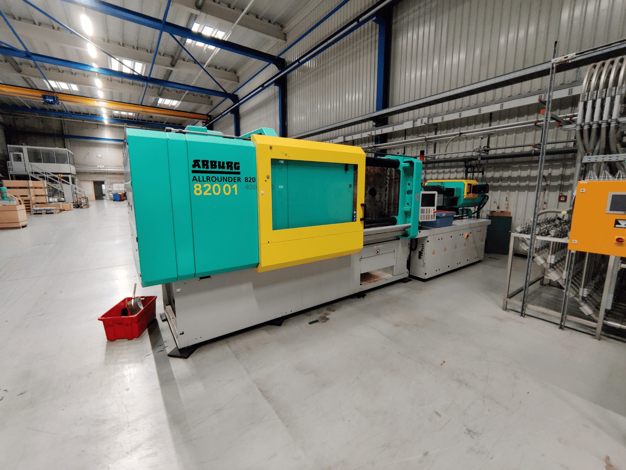 Hidraulinės liejimo mašinos "Arburg 820 S 4000-2100" su ryškiai žaliomis ir geltonomis plokštėmis vaizdas iš priekio.