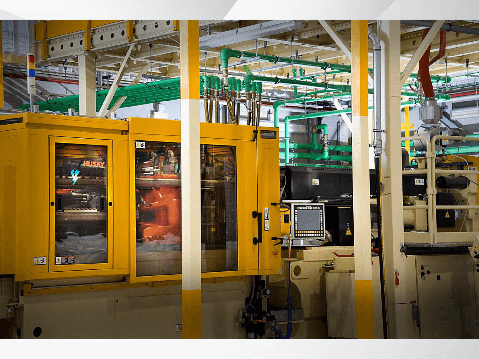 Geltonos spalvos "Husky" pramoninė mašina, iš priekio matomas valdymo skydelis ir vidiniai mechanizmai gamyklos fone.