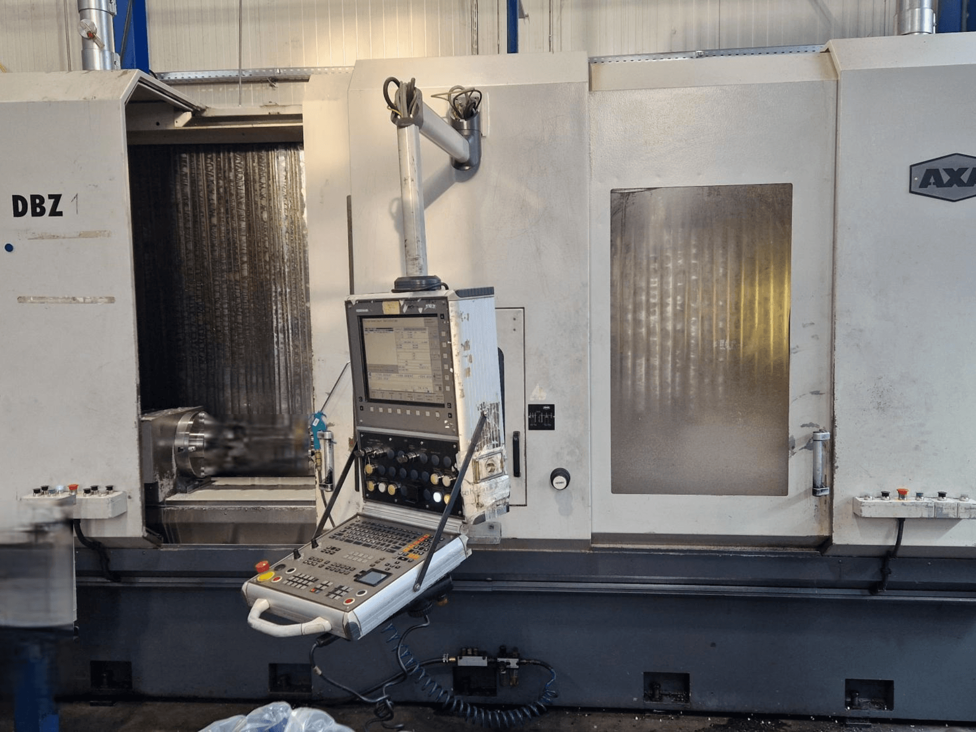 AXA DBZ vertikalusis apdirbimo centras, parodytas kampu iš priekio, su valdymo skydeliu ir matoma pjovimo įrankių zona.