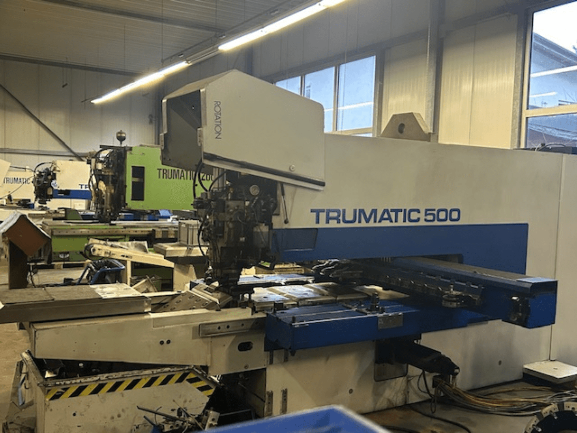 TRUMPF TRUMATIC 500 CNC perforavimo staklės, vaizdas iš priekio, valdymo skydelis ir mechaninės dalys. Pramoninių dirbtuvių aplinka.