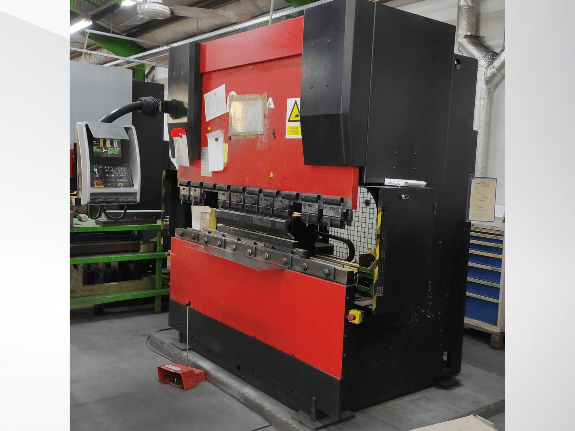 AMADA HFB 5020 raudonos ir juodos spalvų presinis stabdys, priekinis vaizdas, kuriame matyti valdymo skydelis, lenkimo įrankiai ir saugos elementai.