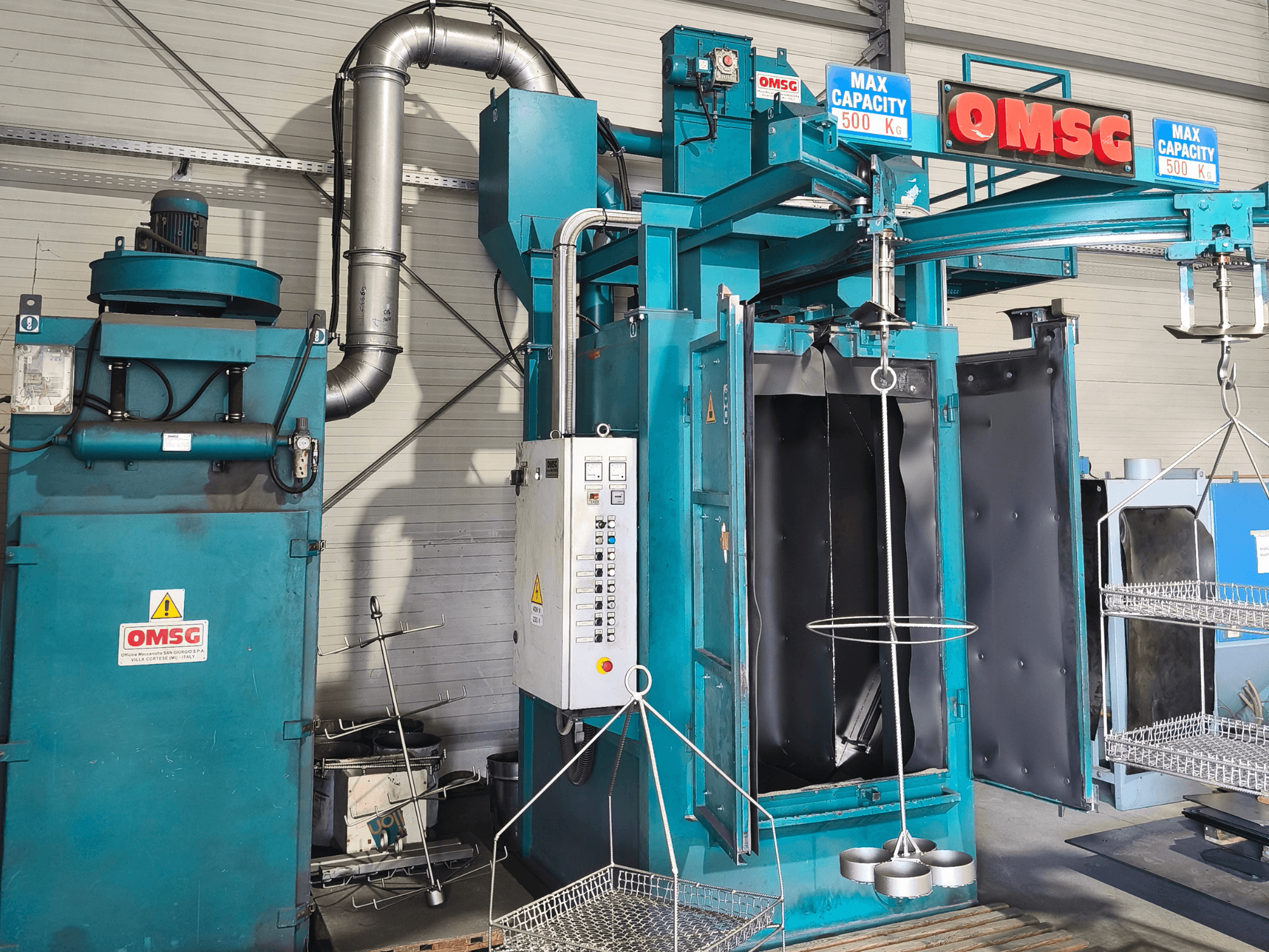 OMSG pramoninė valymo mašina, kurios maksimali keliamoji galia - 500 kg, su valdymo pultu ir atvira kamera detalėms valyti.