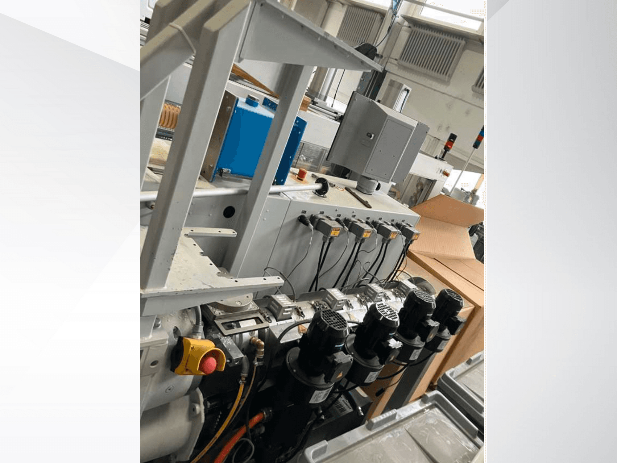 Pramoninių mašinų valdymo skydas su keliais varikliais, matuokliais ir monitoriumi; vaizdas iš šono gamykloje.