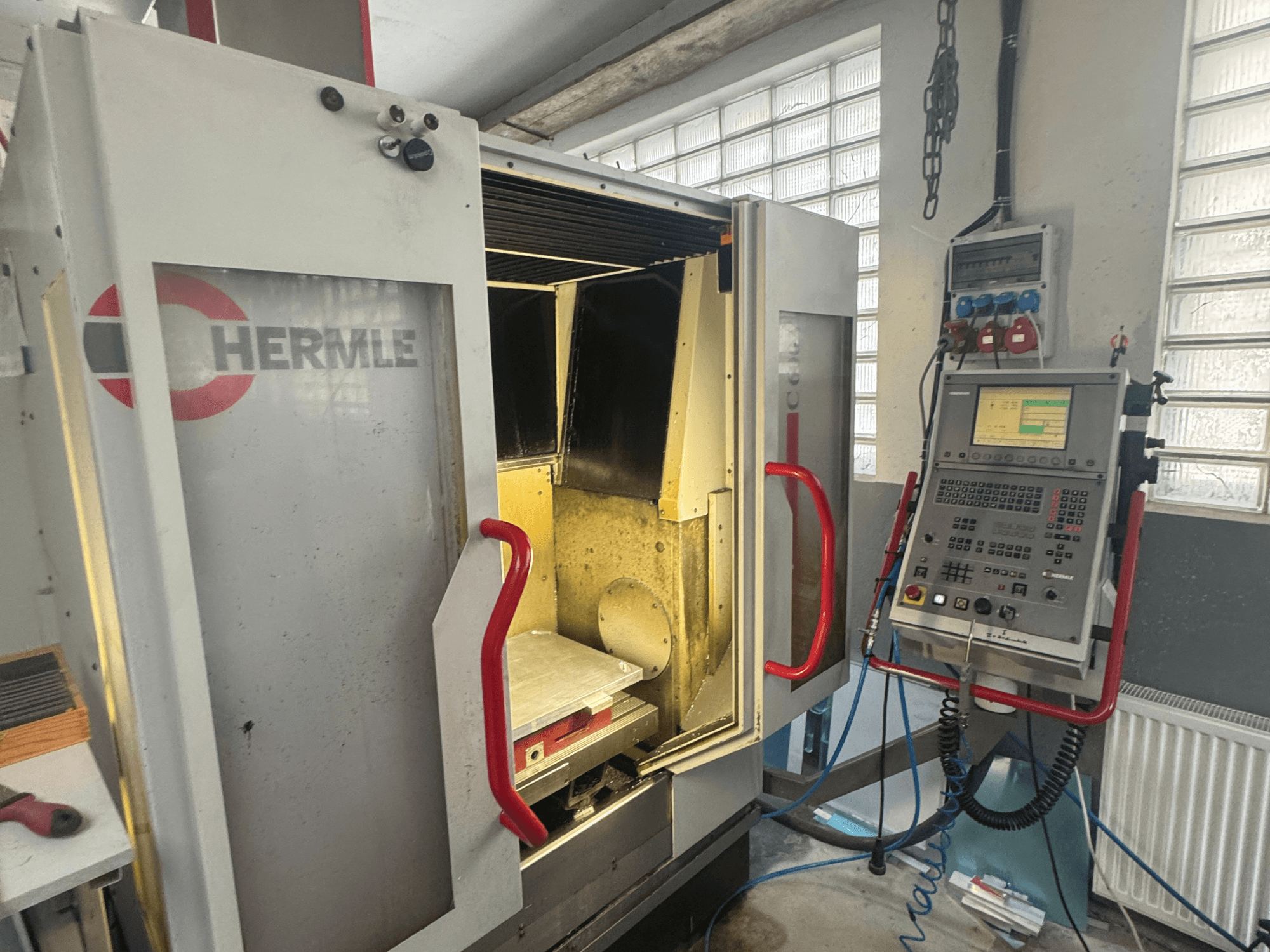 HERMLE C600V vertikalusis apdirbimo centras, priekinis vaizdas, kuriame matomos atidarytos durys, valdymo skydelis ir vidinė darbo zona.