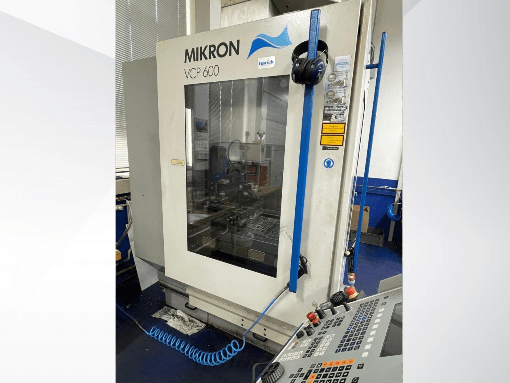 Mikron VCP 600 CNC staklės, vaizdas iš priekio, valdymo skydelis su mygtukais ir už stiklo matoma apdirbimo zona.