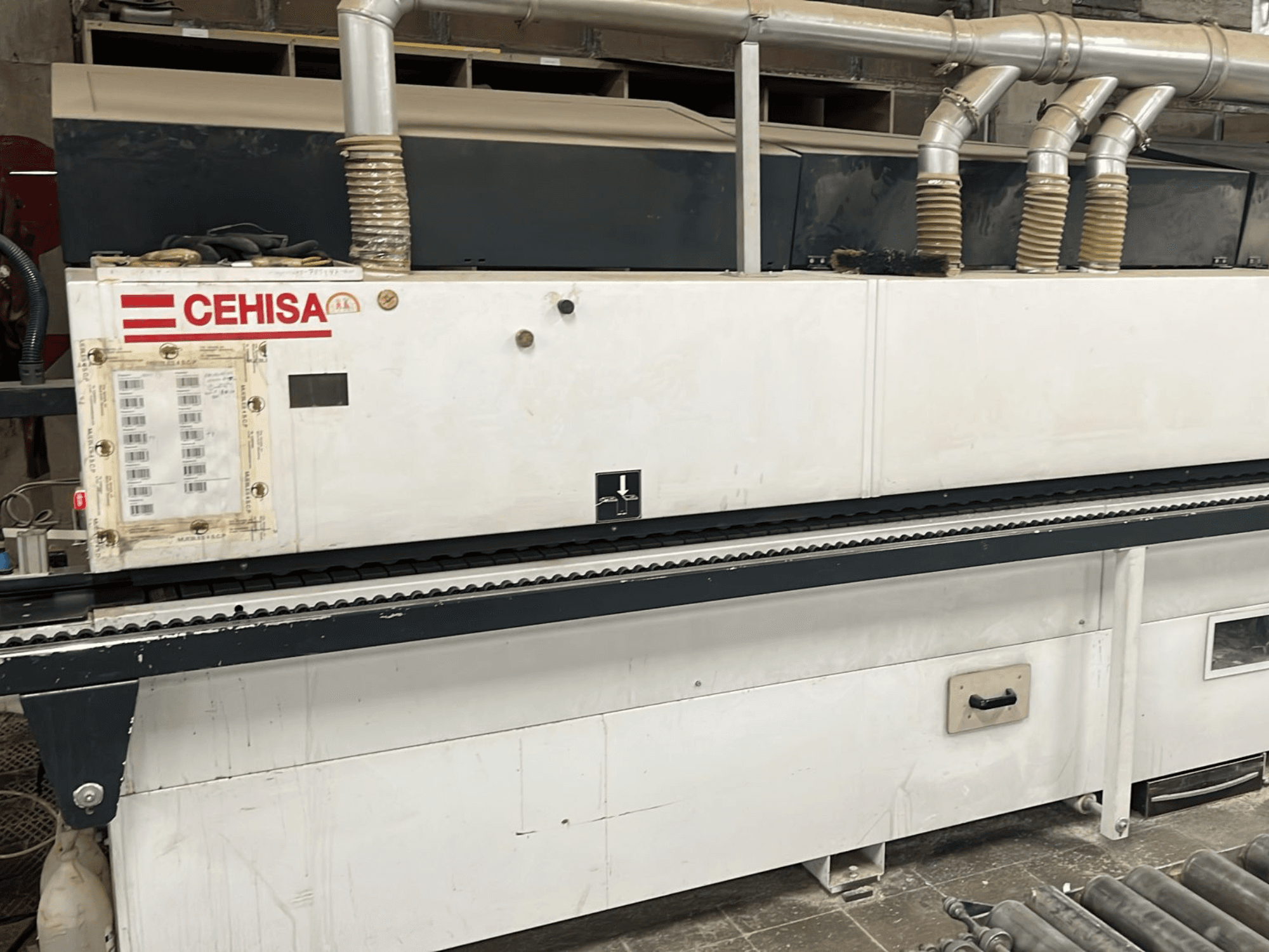 „CEHISA PRO 12 CONCEPT“ kraštų apdirbimo staklės, vaizdas iš priekio, kuriose matyti valdymo pultas, dulkių išsiurbimo vamzdžiai ir konvejerio juosta.