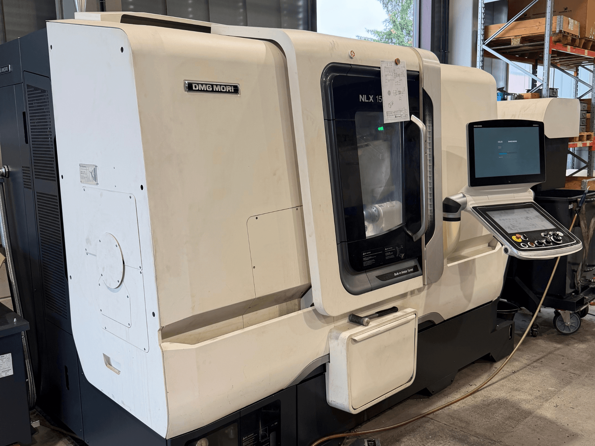 DMG MORI NLX1500MC/500 horizontalios tekinimo staklių vaizdas iš priekio, per skaidrų dangtį matomas valdymo pultas ir suklio sritis.