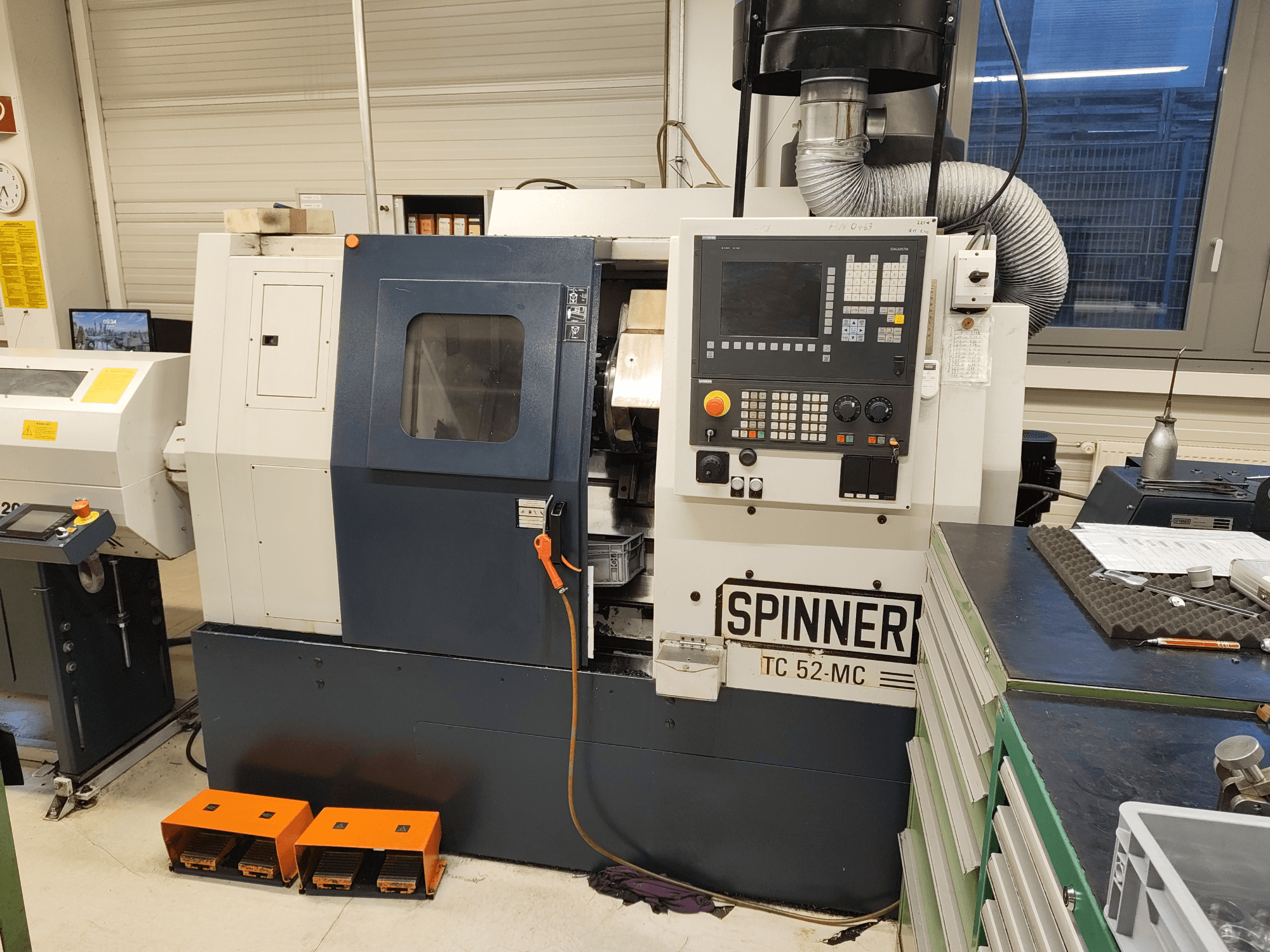 Horizontali tekinimo staklė „SPINNER TC 52 MC“ dirbtuvėse, vaizdas iš priekio, kuriame matomas valdymo pultas, apdirbimo zona ir saugos įranga.