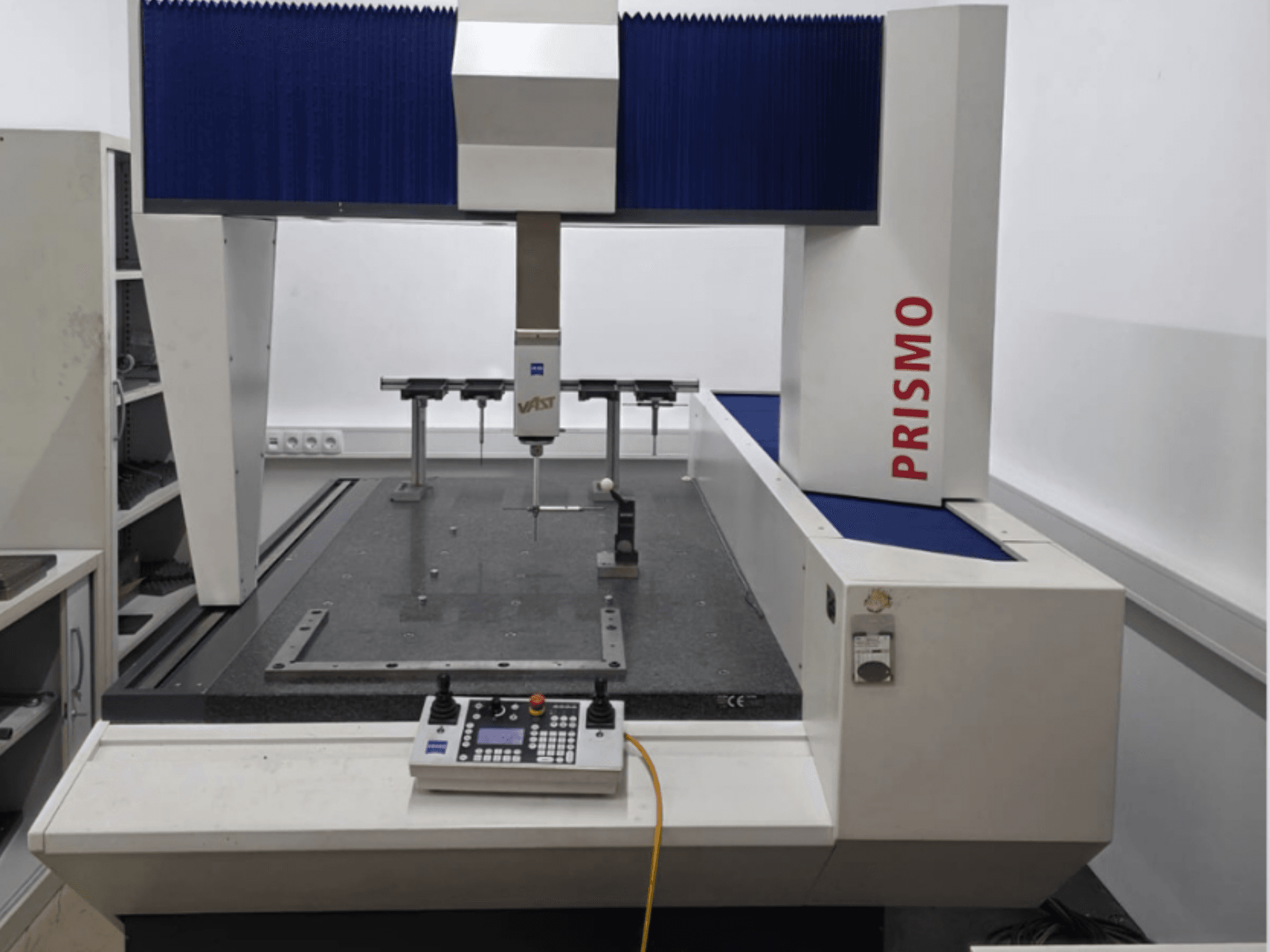 ZEISS PRISMO 700 koordinačių matavimo mašina iš priekio, su zondu ir valdymo skydeliu ant granitinio pagrindo.