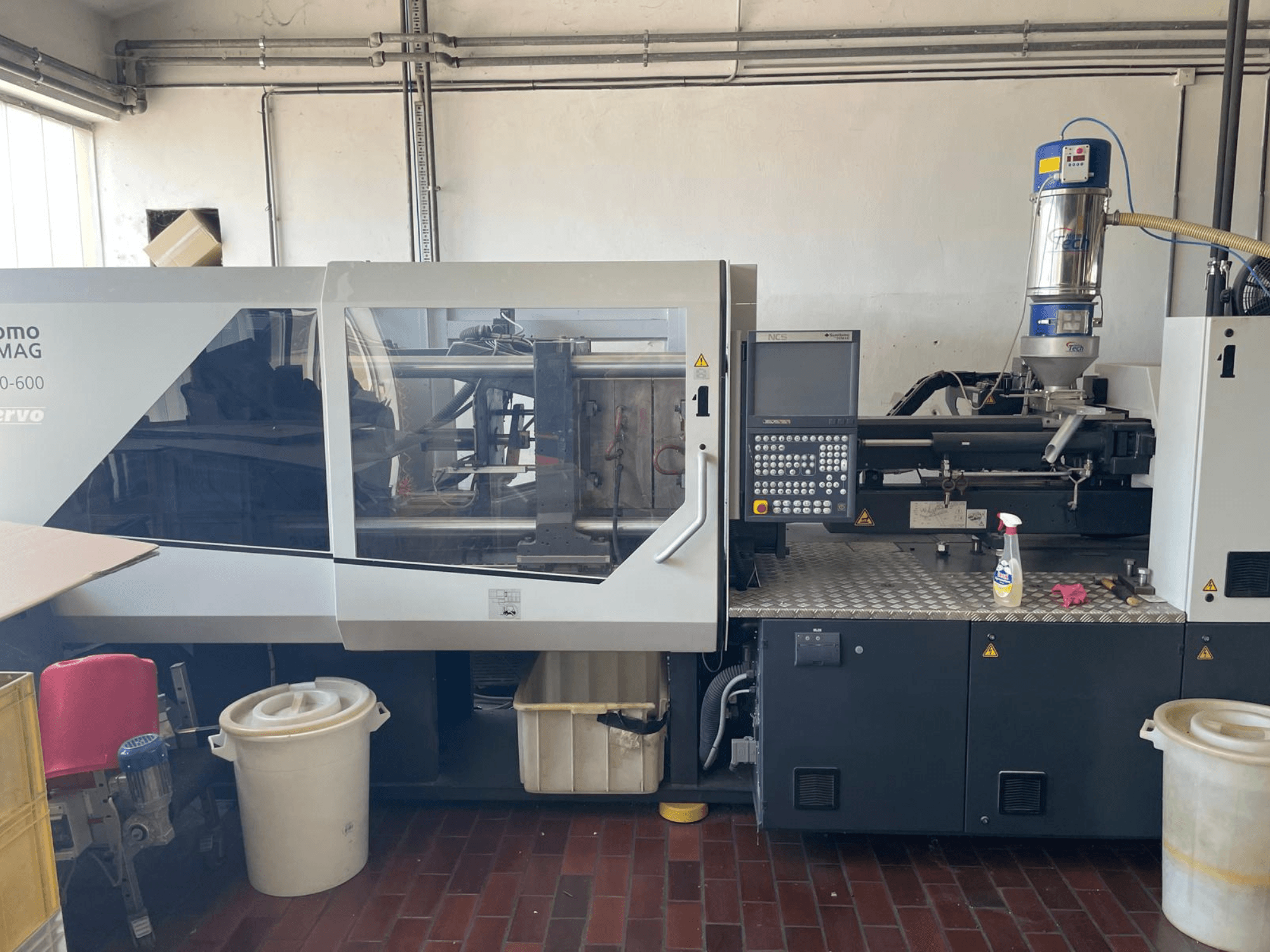 SUMITOMO SHI DEMAG Systec 160/520-600 hidraulinės liejimo mašinos su valdymo pultu ir padavimo įrenginiu vaizdas iš priekio.
