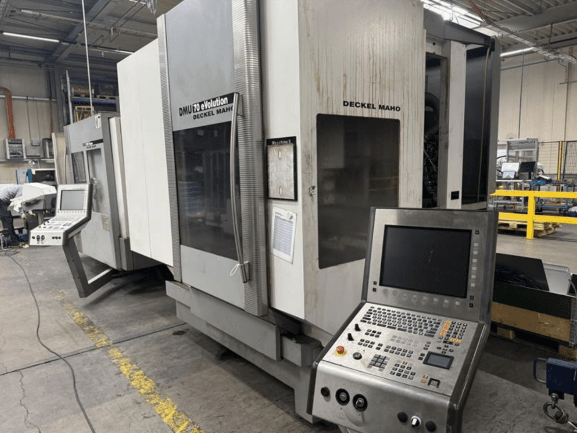 Gamybos įmonėje esančių "Deckel Maho DMU 70 eVOLUTION CNC" staklių su valdymo pultu vaizdas iš priekio.