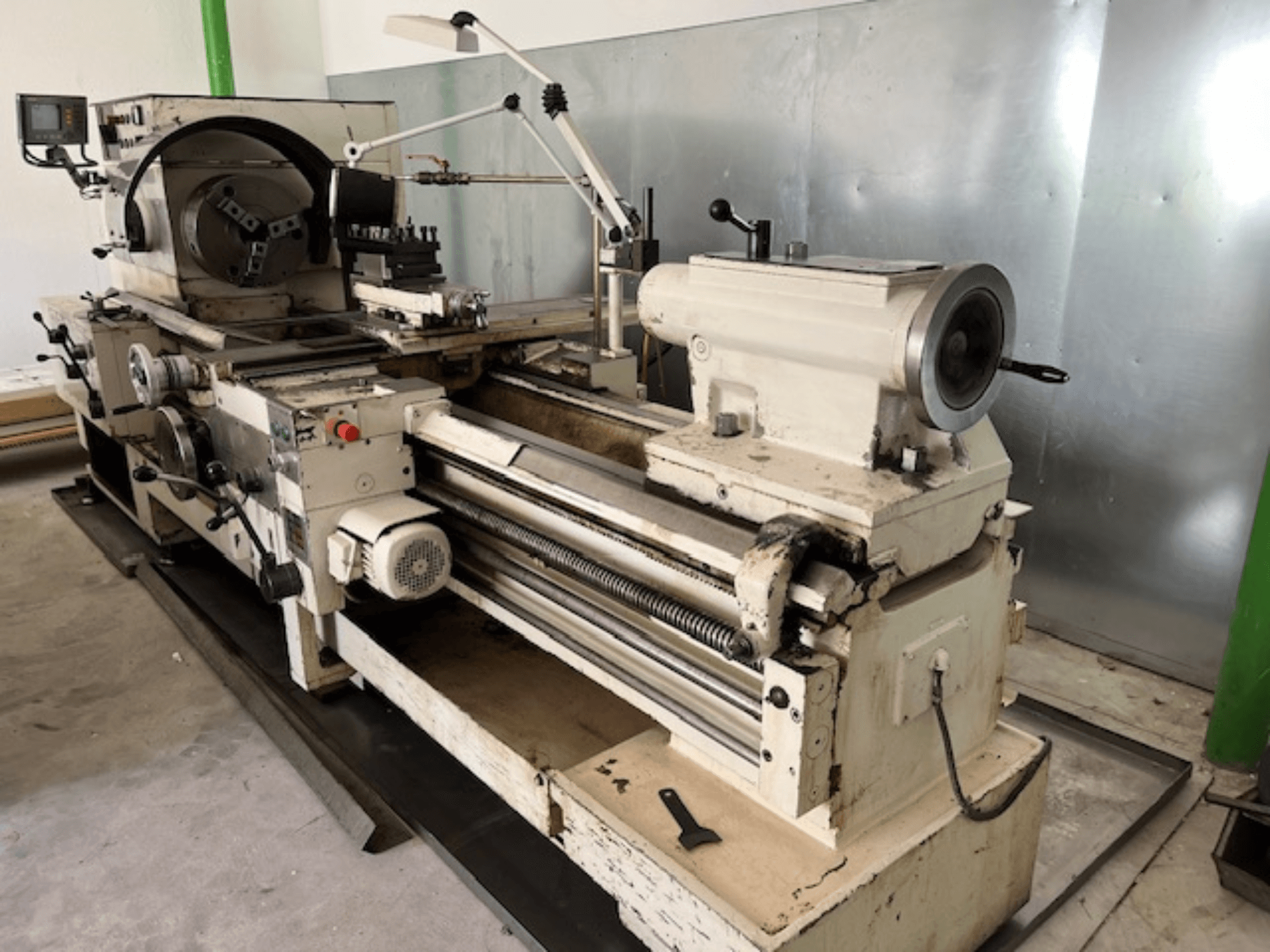 Senovinės metalo tekinimo staklės su valdymo skydeliu ir įrankiais, šoninis vaizdas, kuriame matyti veikimo elementai ir metalo apdaila.