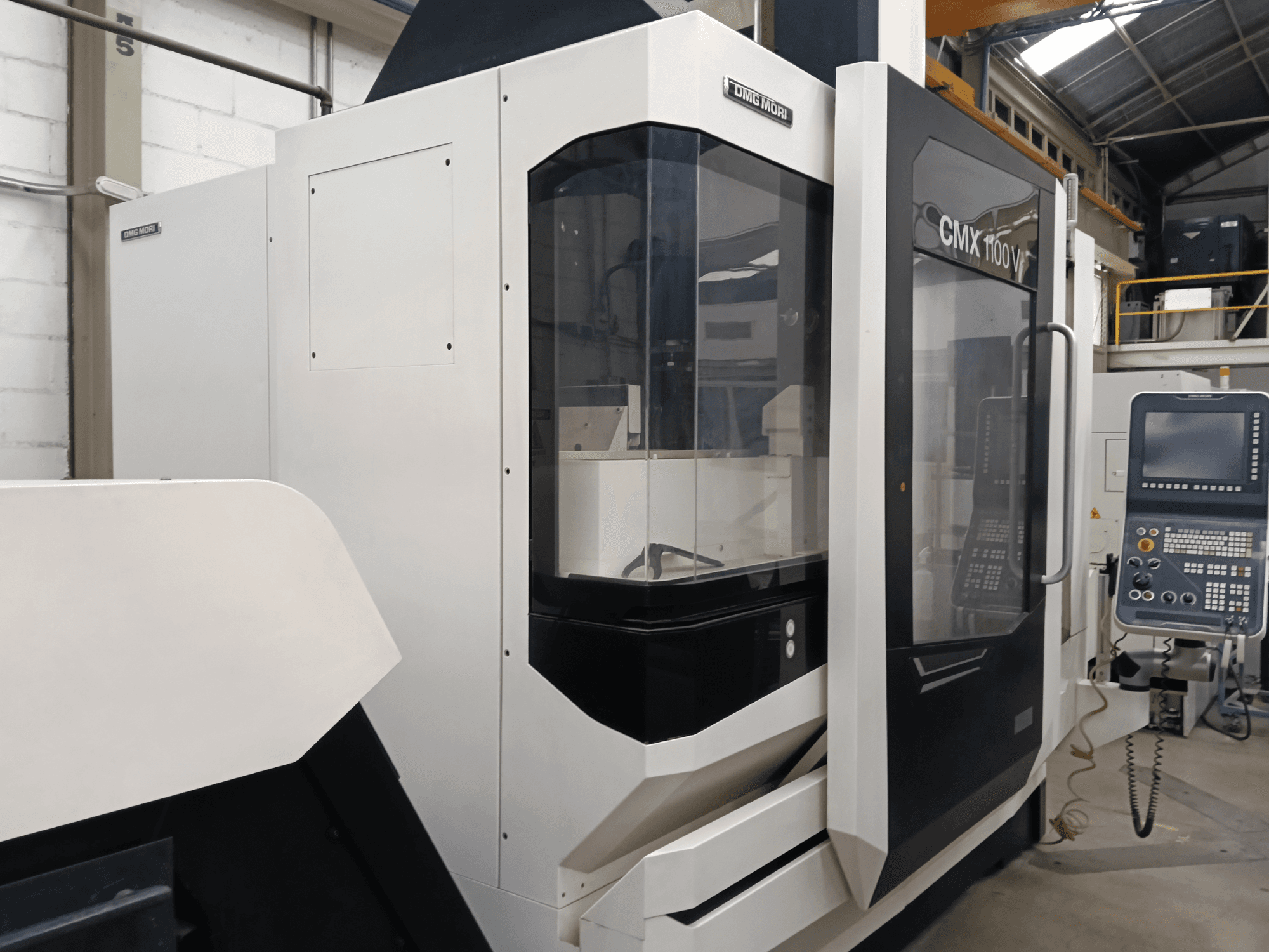 Vertikalusis apdirbimo centras „DMG MORI MORI CMX 1100 V“, vaizdas iš priekio, kuriame matomas valdymo pultas ir stiklinis gaubtas.