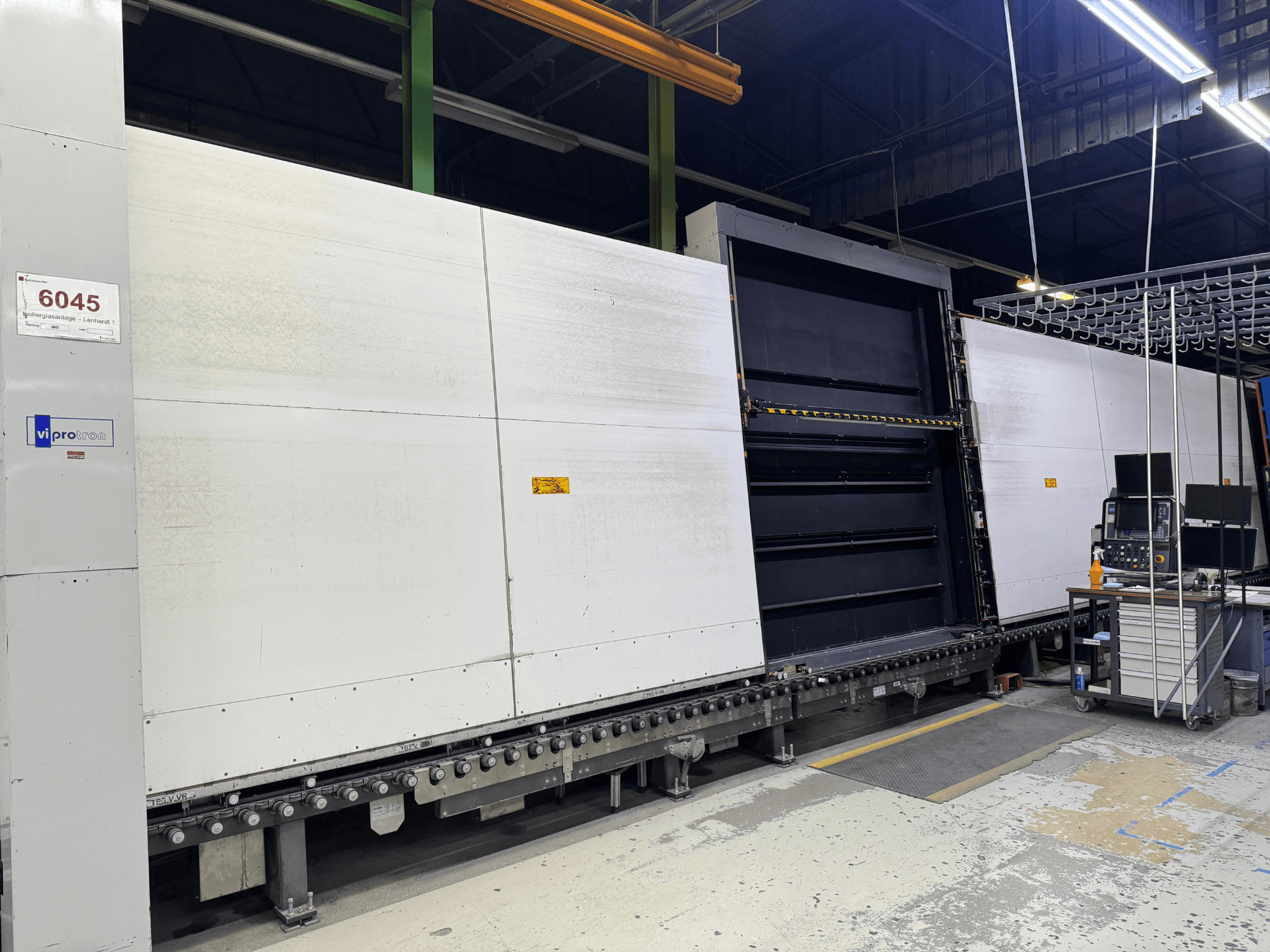 "Vipro" liejimo mašinos priekinis vaizdas su atviru skydeliu, kuriame matoma darbinė įranga ir šalia jos esanti darbo vieta. 6045 modelis.