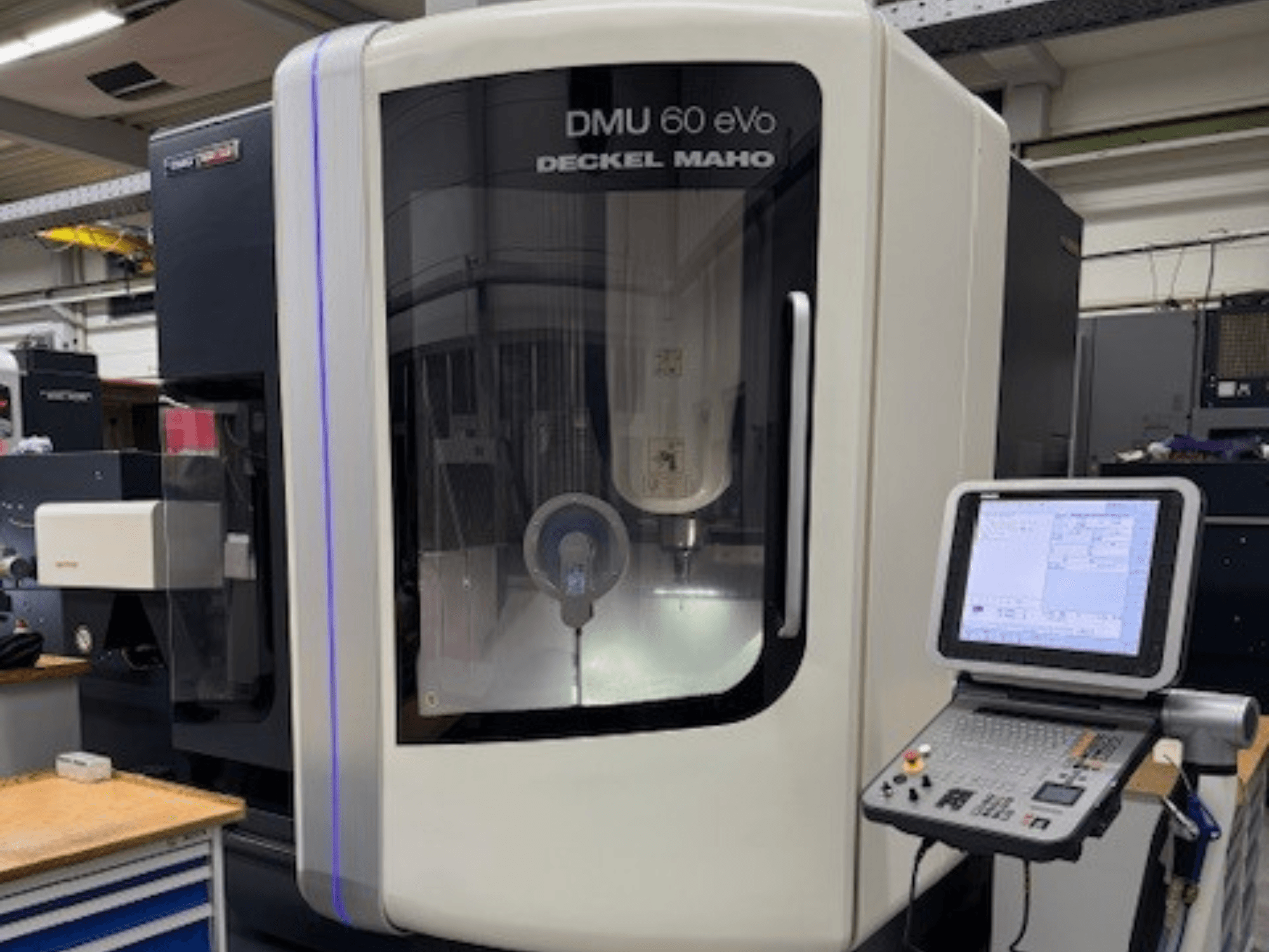 DECKEL MAHO DMU 60 eVo, priekinis CNC frezavimo staklių vaizdas su valdymo skydeliu ir ekranėliu, kuriame matomi tikslūs komponentai.