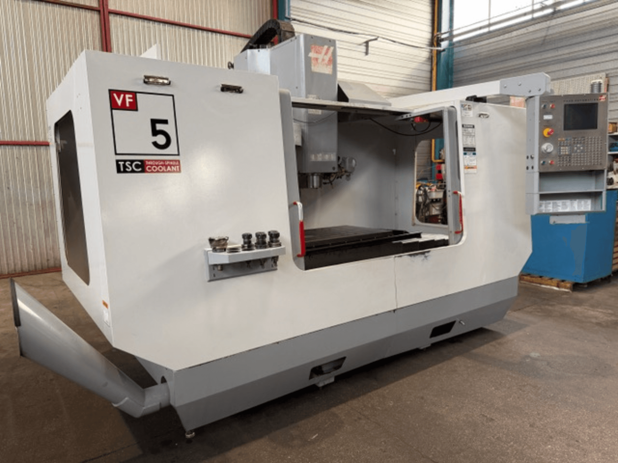 Vertikalusis apdirbimo centras „HAAS VF5-HE“, vaizdas iš priekio, kuriame matoma TSC aušinimo sistema ir operatoriaus valdymo pultas.