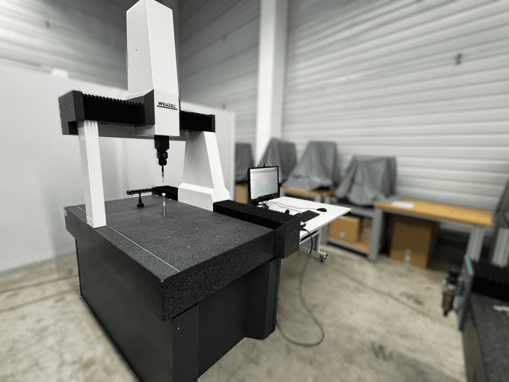 "Wenzel LH 54" koordinatinės matavimo mašinos šoninis vaizdas: zondas ir kompiuterio sąsaja ant pilko pagrindo.