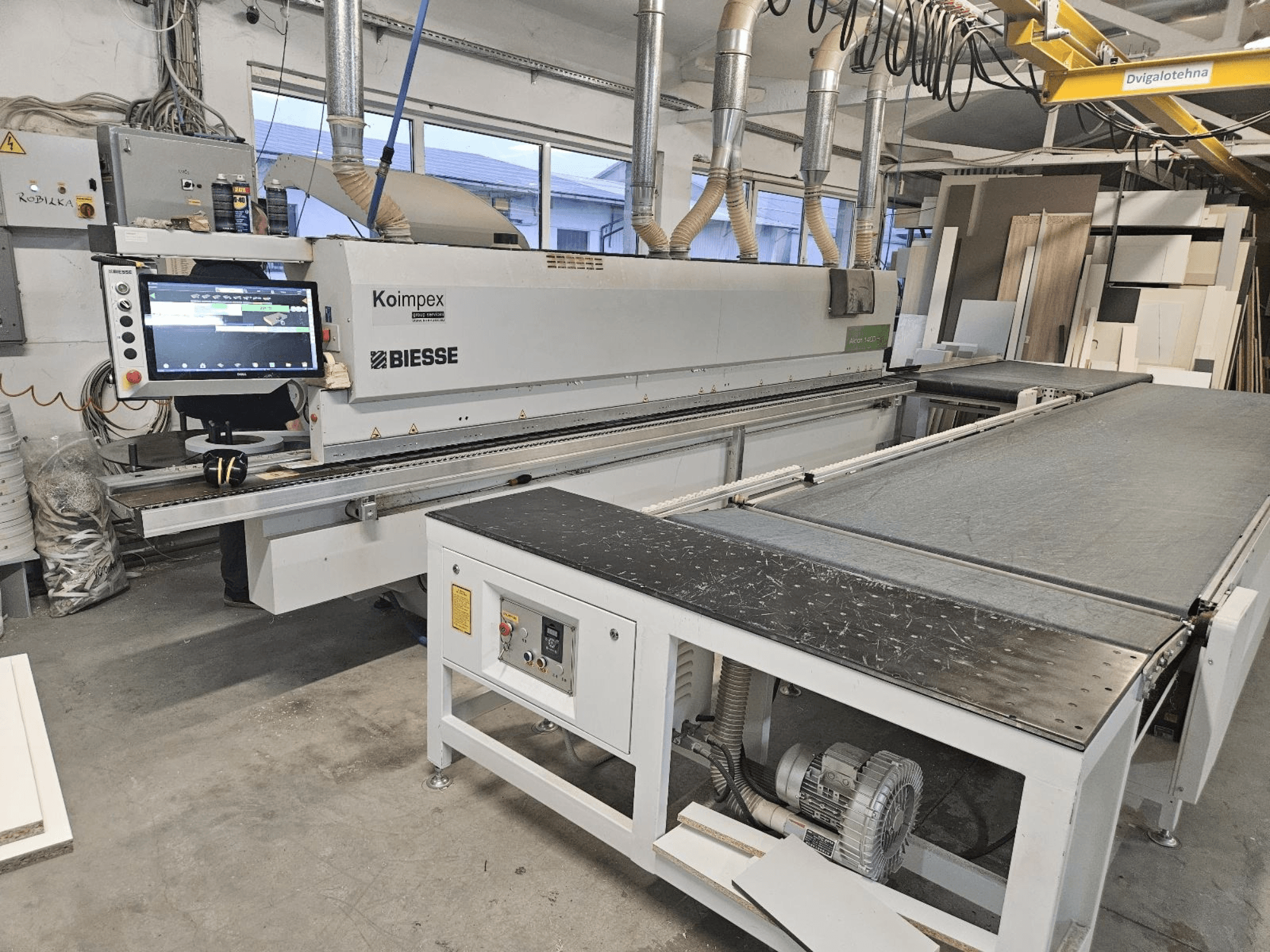 BIESSE Akron 1440 BIESSE Akron 1440 Kantų apipjaustymo mašina dirbtuvėse, šoninis vaizdas, kuriame matomas valdymo skydelis ir konvejerio juosta.