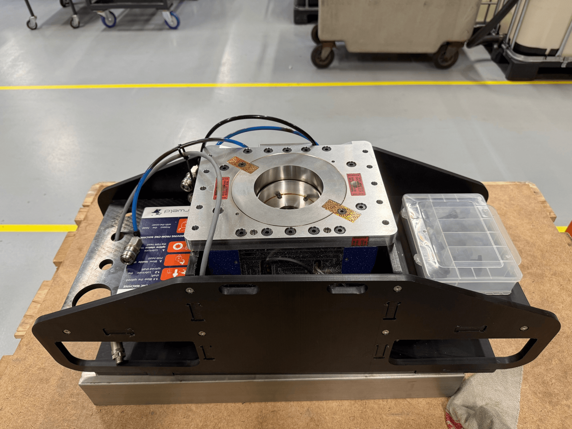 Mechaniškai apdirbtas metalinis komponentas su mėlynais kabeliais, priedų dėklu ir plokščiu pagrindu, parodytas iš viršaus, idealiai tinka mechaninėms programoms.