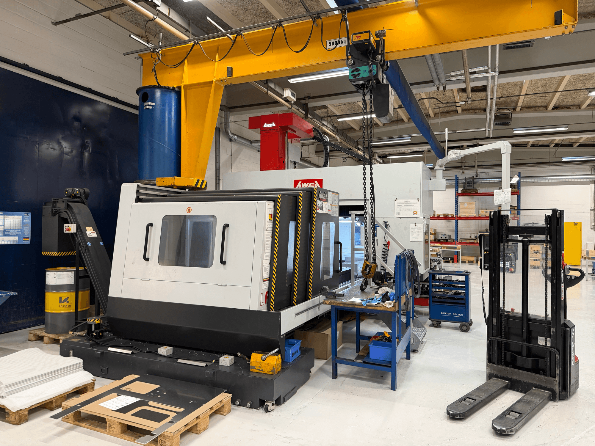 Portalinės frezavimo staklės AWEA LP3016YF, vaizdas iš priekio, su įrankiais, mėlynu rezervuaru ir darbo vieta fone.