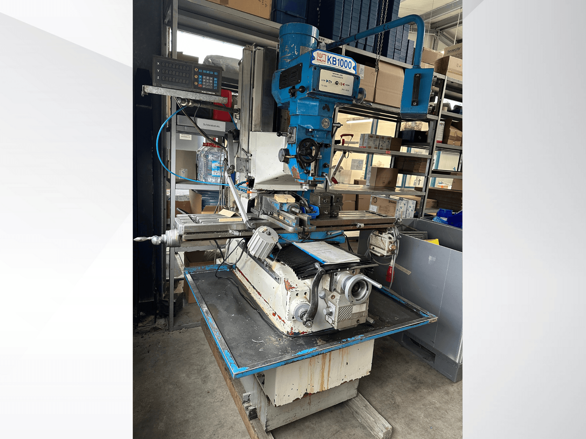 Vertikalios frezavimo staklės KB1000 su skaitmeniniu ekranu, šoninis vaizdas, kuriame matyti stalas, suklys ir įrankių laikiklis.