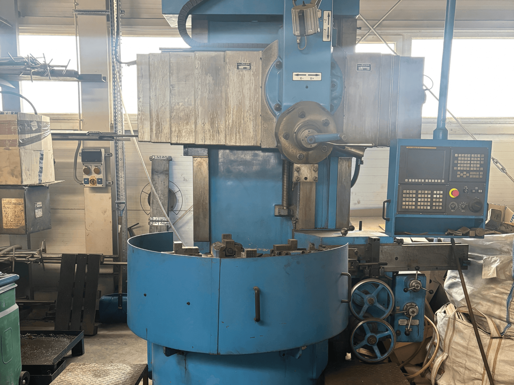 Nežinomo prekės ženklo pramoninės frezavimo staklės, vaizdas iš priekio, mėlyna išorė ir skaitmeninis valdymo skydelis.