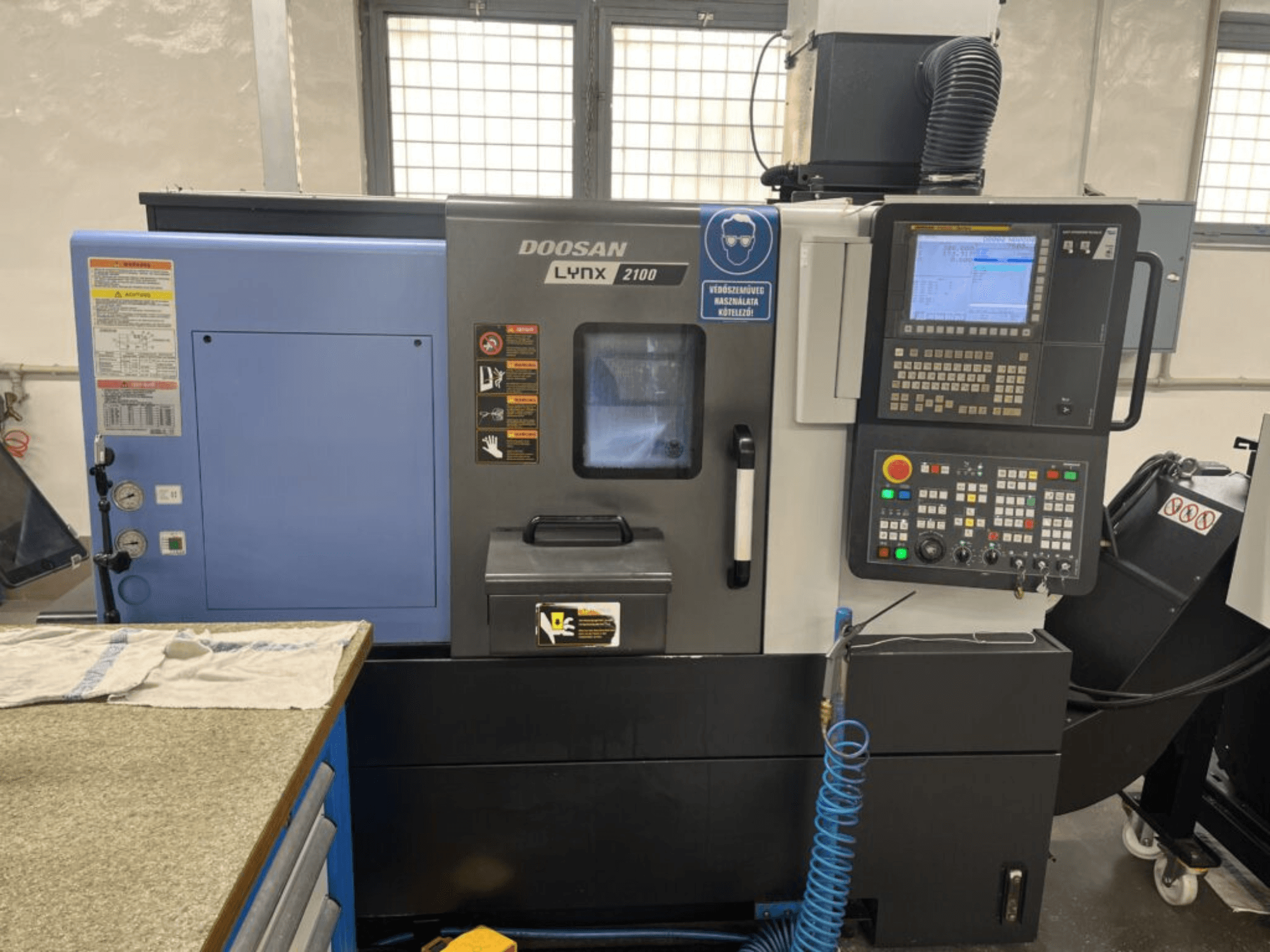 DOOSAN Lynx 2100A horizontalios tekinimo staklės, priekinis vaizdas, kuriame matyti valdymo skydelis, operatoriaus sąsaja ir staklių funkcijos.