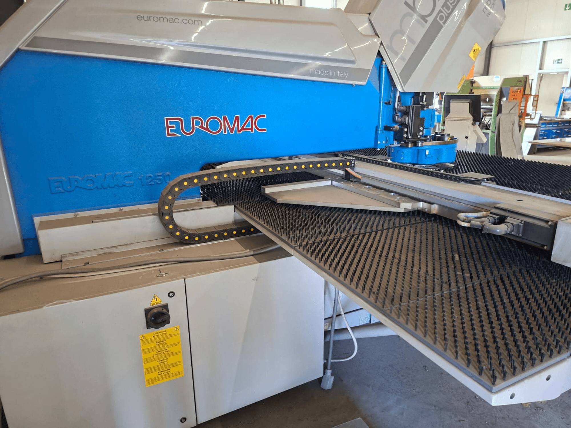CNC perforavimo staklės "Euromac MBX 6 Plus 1250/30-2250", priekinis vaizdas, kuriame matomas valdymo skydelis ir juodas guminis paviršius.