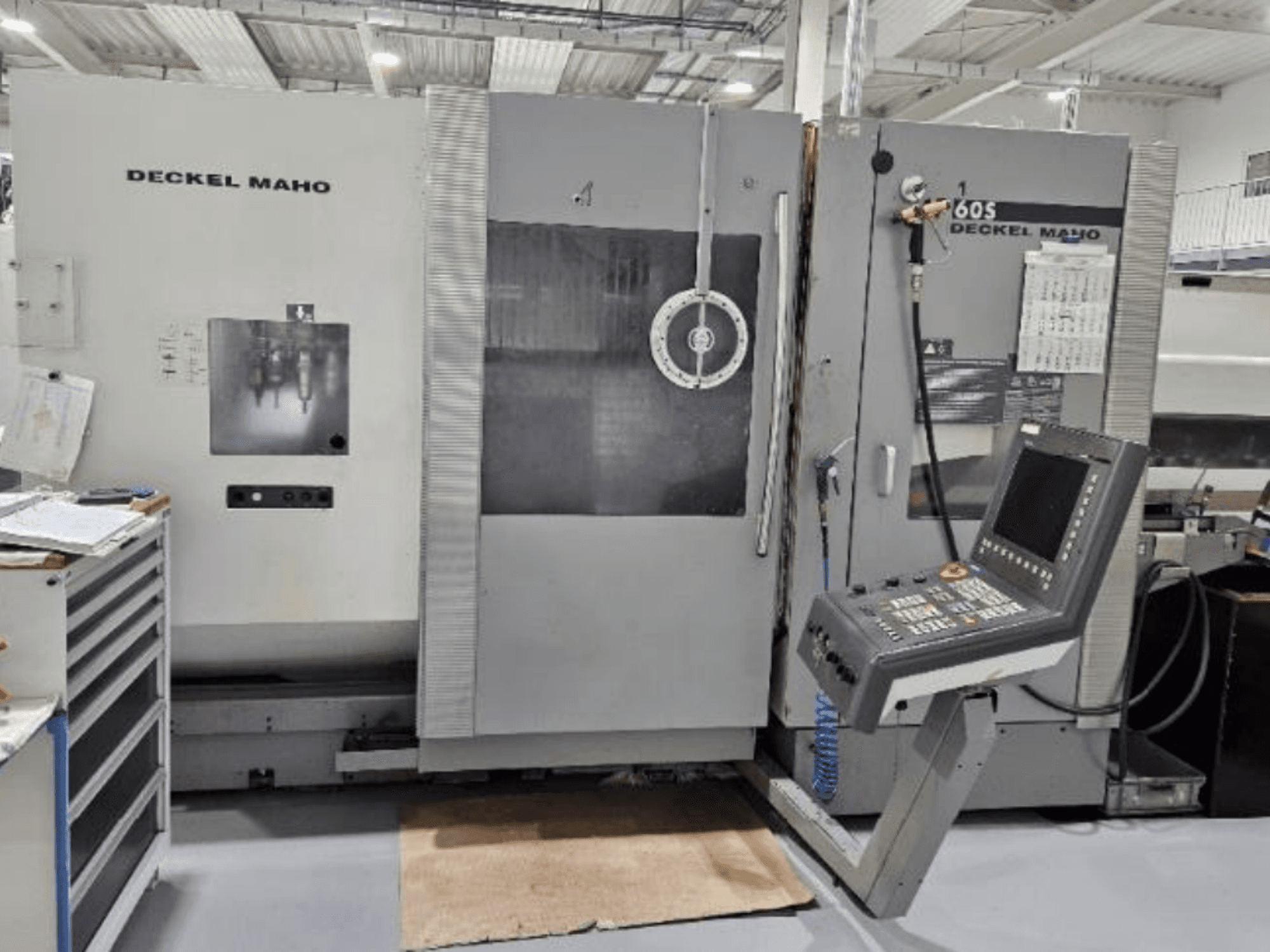 DECKEL MAHO 60S CNC staklių vaizdas iš priekio su valdymo skydeliu, matomi įrankiai, dirbtuvių aplinka.