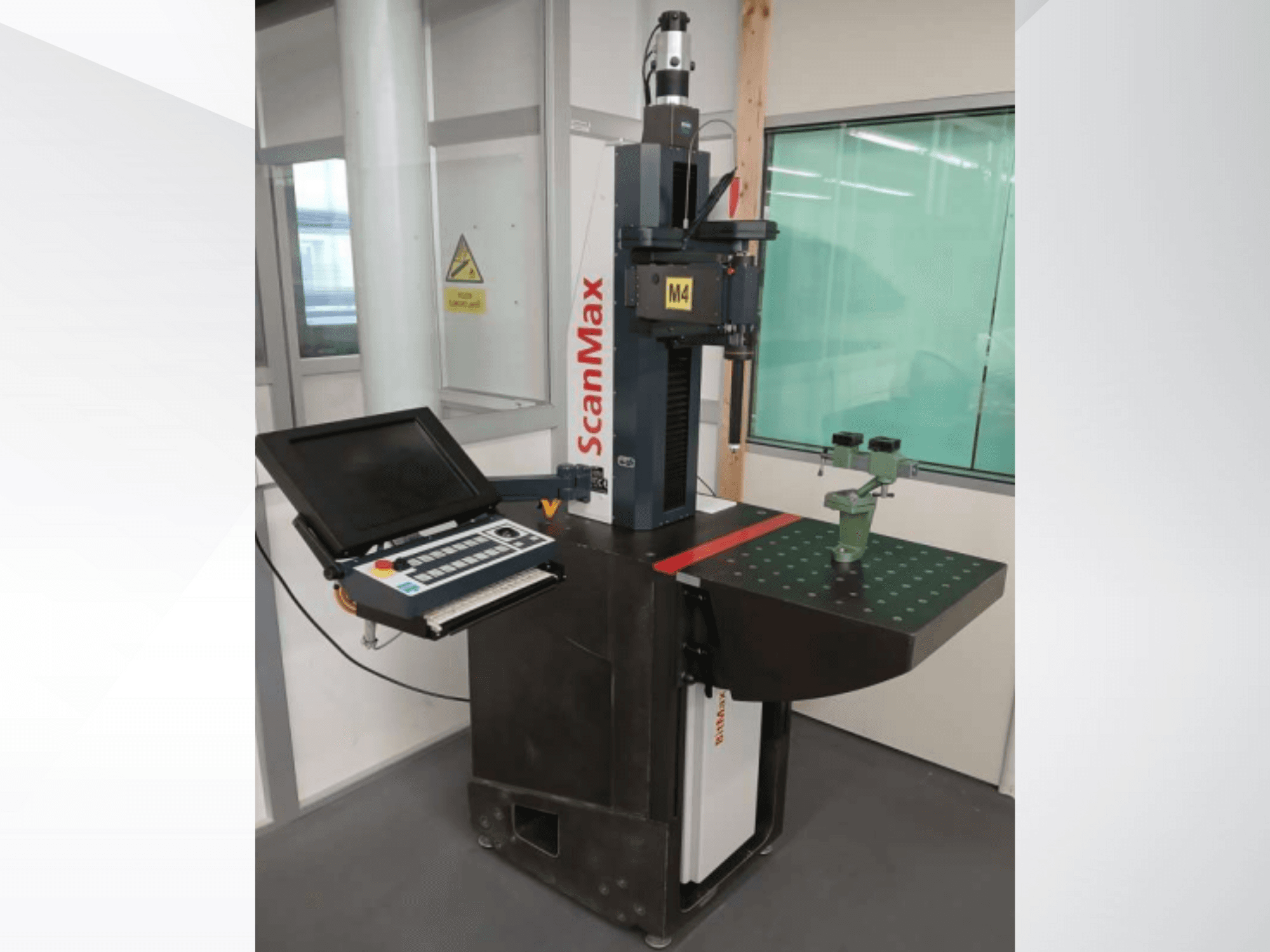 ScanMax M4 matavimo aparatas, vaizdas iš priekio su valdymo skydeliu ir žalios spalvos kalibravimo įtaisu ant punktyrinio darbo stalo.