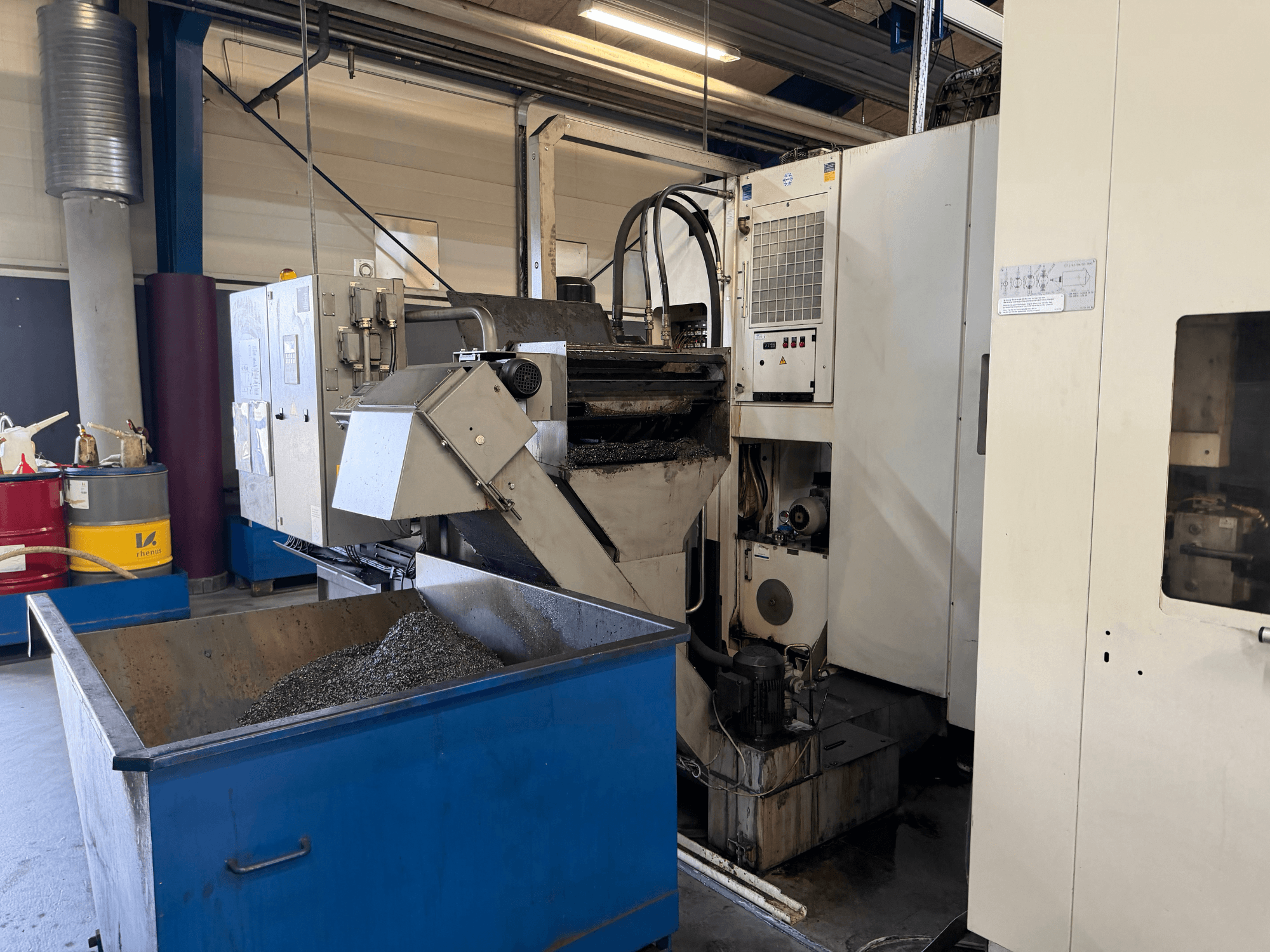 Horizontalaus apdirbimo centro HELLER MCH 250 vaizdas iš priekio, matoma metalinio aušinimo skysčio perdirbimo talpykla ir valdymo skydelis.