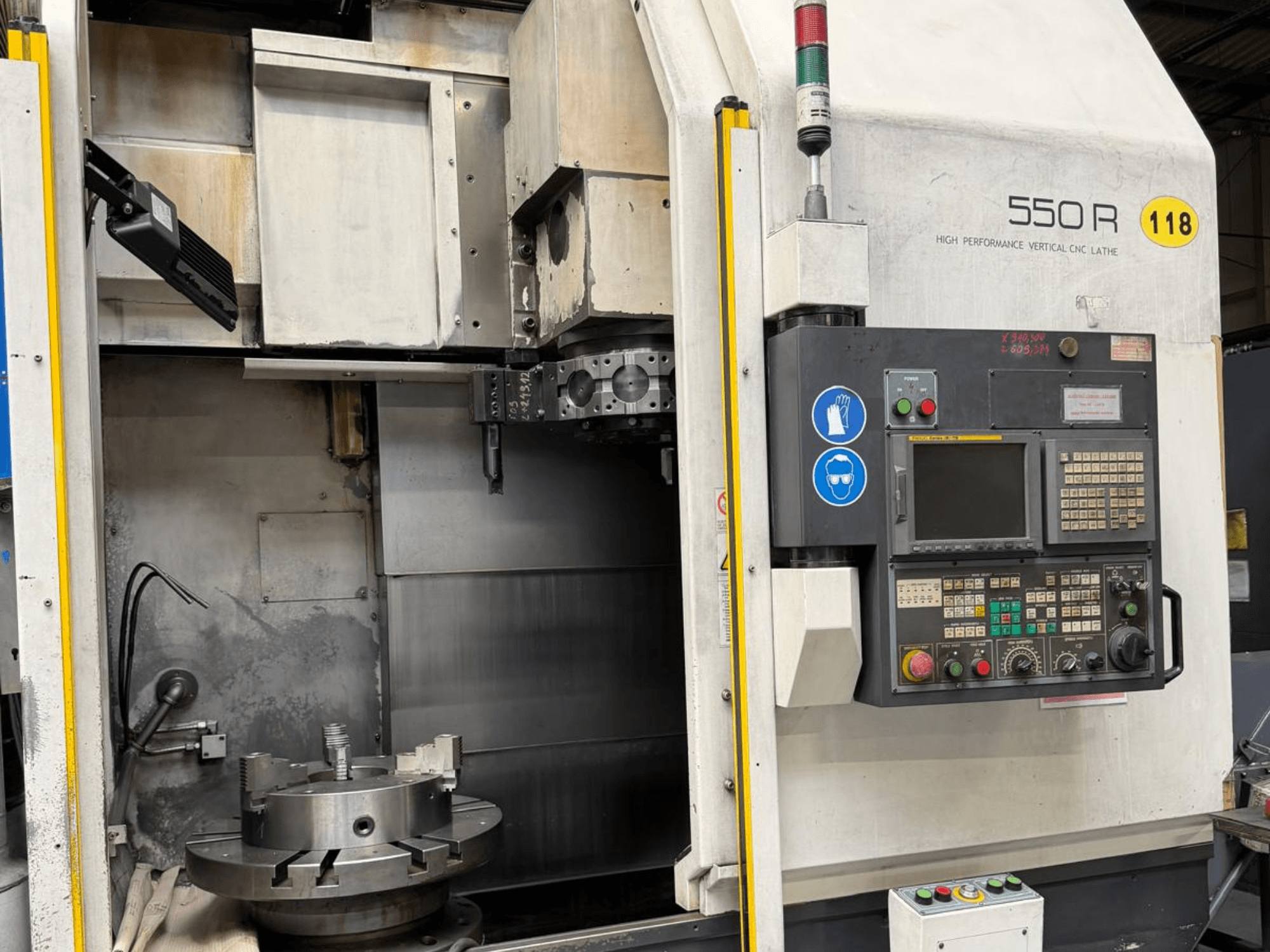 Didelio našumo vertikalios CNC staklės 550 R, priekinis vaizdas, kuriame matomas valdymo skydelis, besisukantis griebtuvas ir darbiniai komponentai.