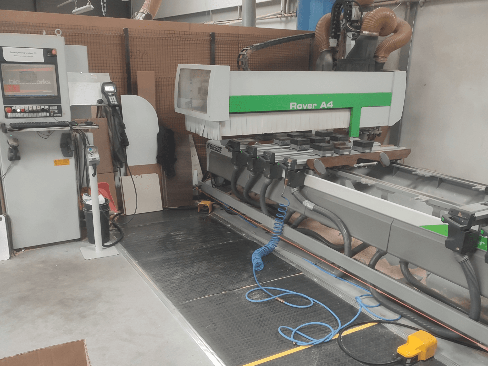„BIESSE Rover A4“ CNC medienos apdirbimo centras, vaizdas iš šono, kuriame matomas valdymo pultas, vakuuminiai tvirtinimo įtaisai ir dulkių surinkimo sistema.