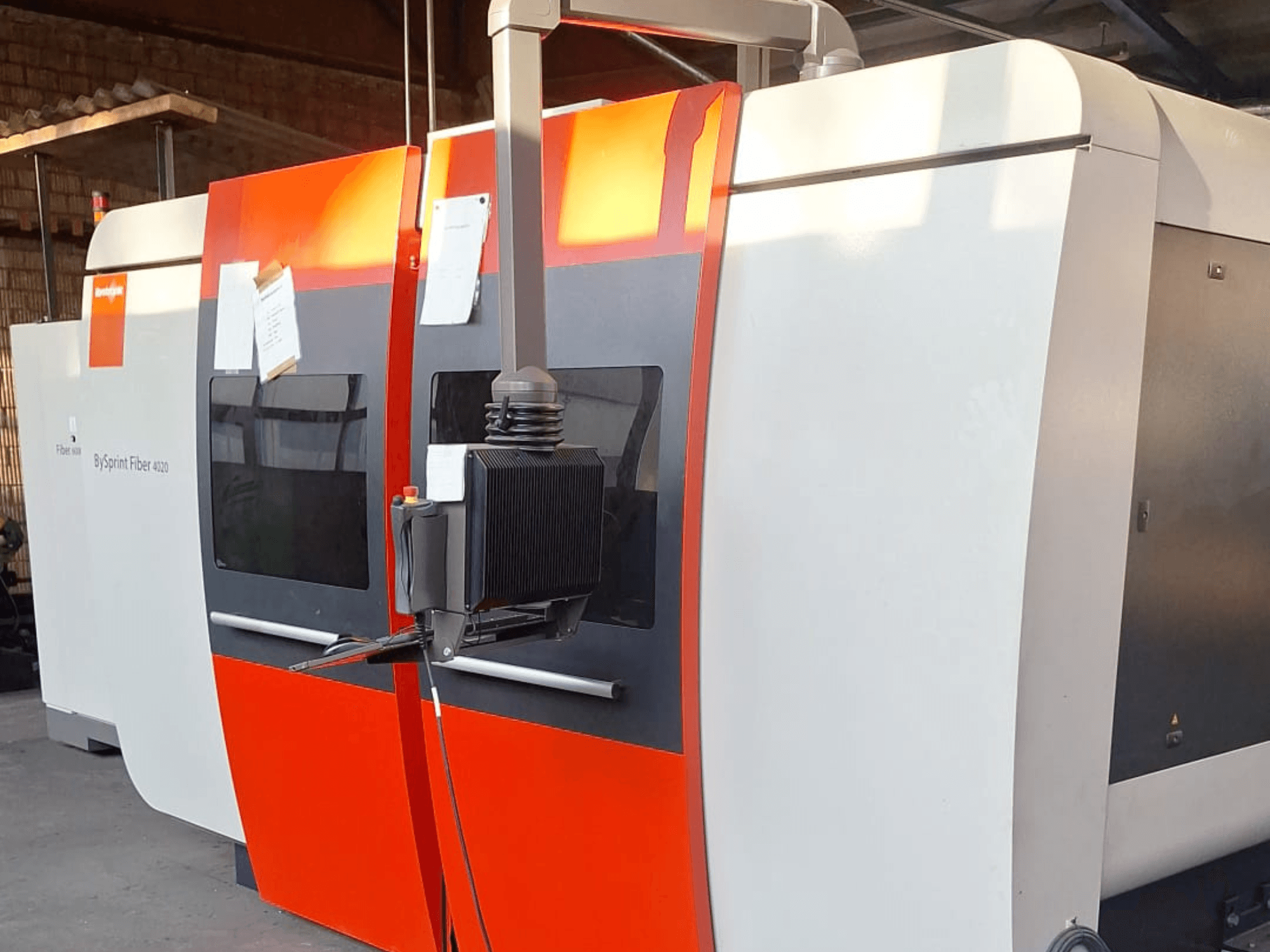 "BySprint Fiber 4020" lazerinio pjovimo mašina, vaizdas iš šono, raudonos ir baltos spalvos išorė, matomas detalus valdymo skydelis.