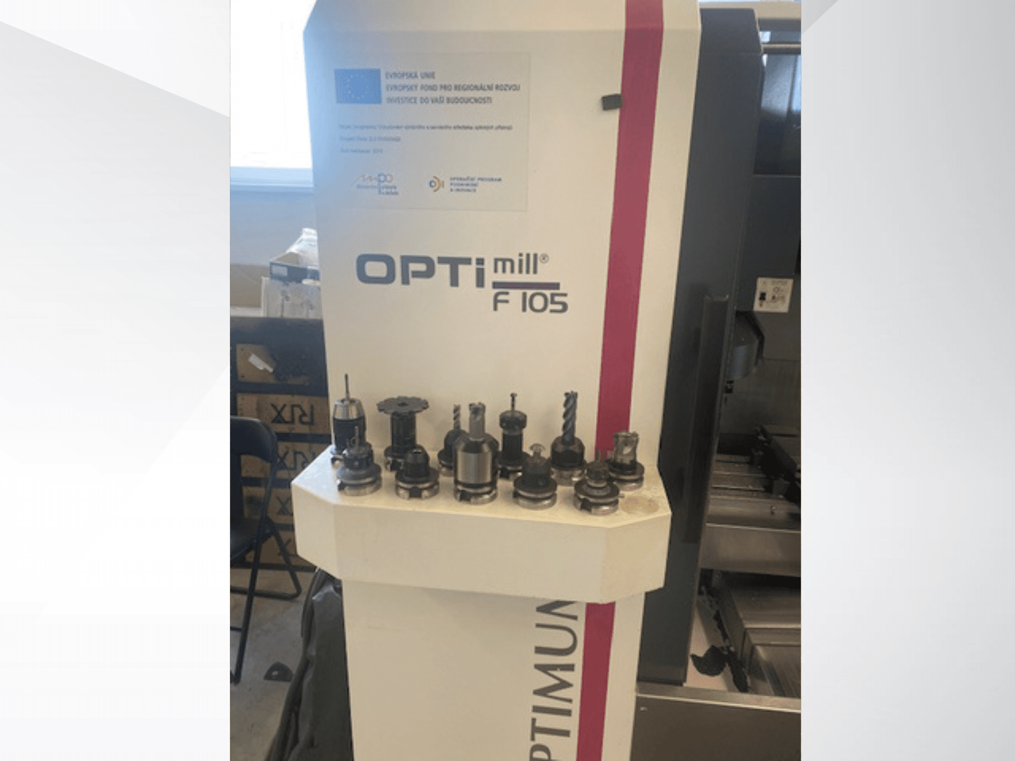 „Optimum Optimill F105“ vertikaliojo apdirbimo centro vaizdas iš priekio, šone matomi įvairūs pritvirtinti įrankiai.