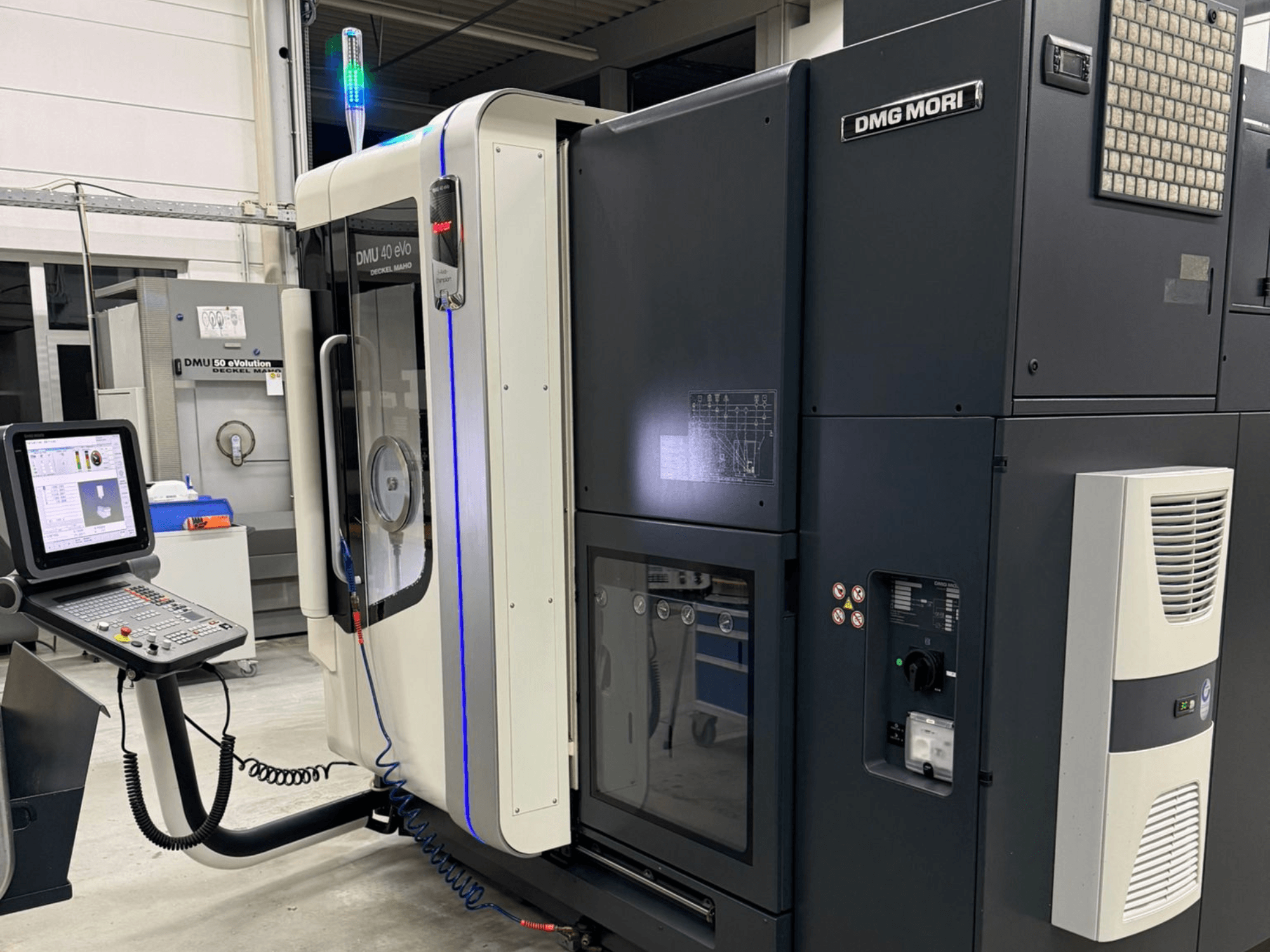 DMG MORI DMU 40 eVo mašina, priekinis vaizdas, kuriame matomi valdikliai, LED indikatoriai ir elegantiškas dizainas, pabrėžiantis pramonines savybes.