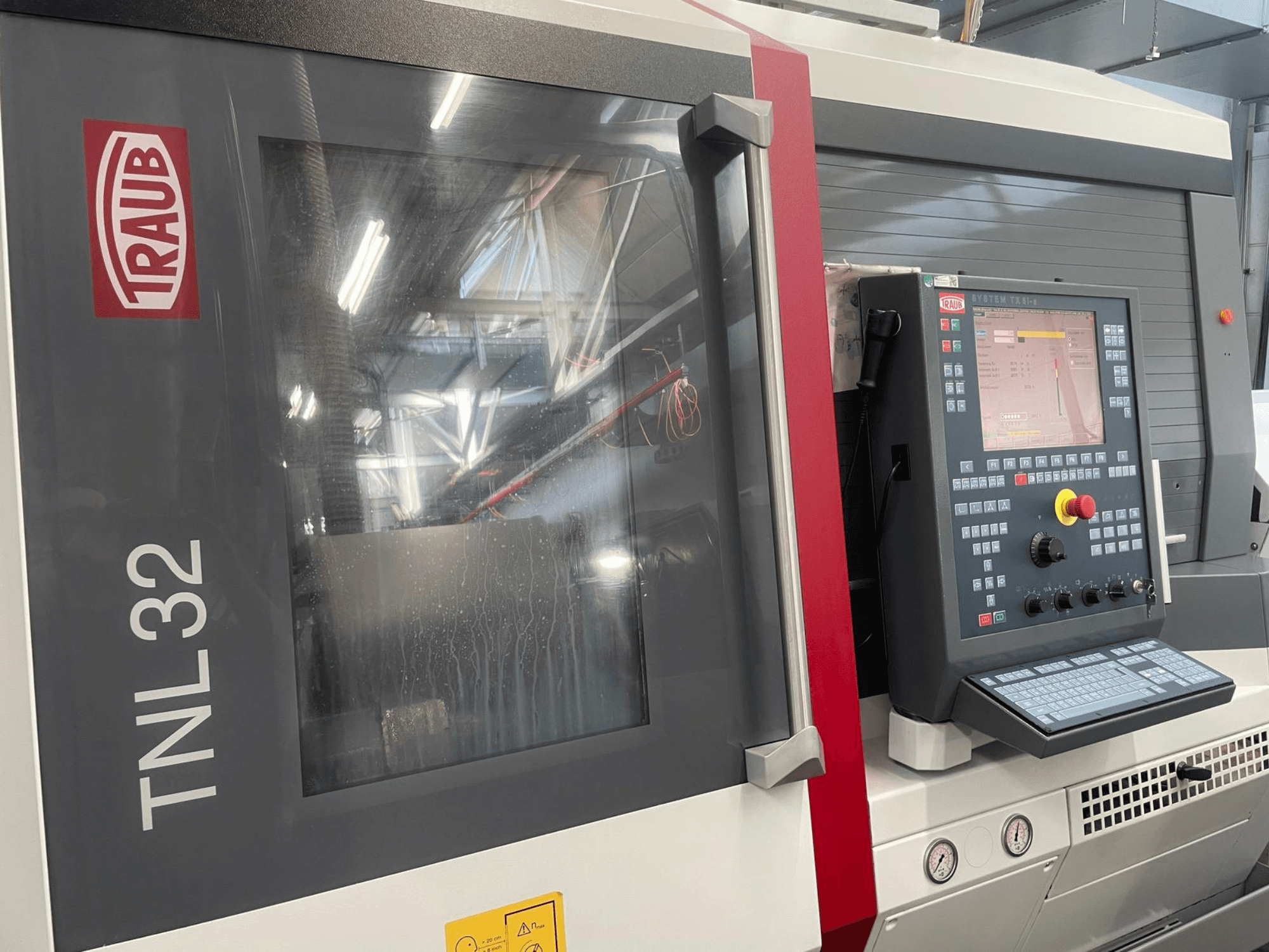 Traub TNL32 CNC tekinimo staklių priekinis vaizdas: valdymo skydelis su mygtukais, ekranas ir aptakus metalinis korpusas.