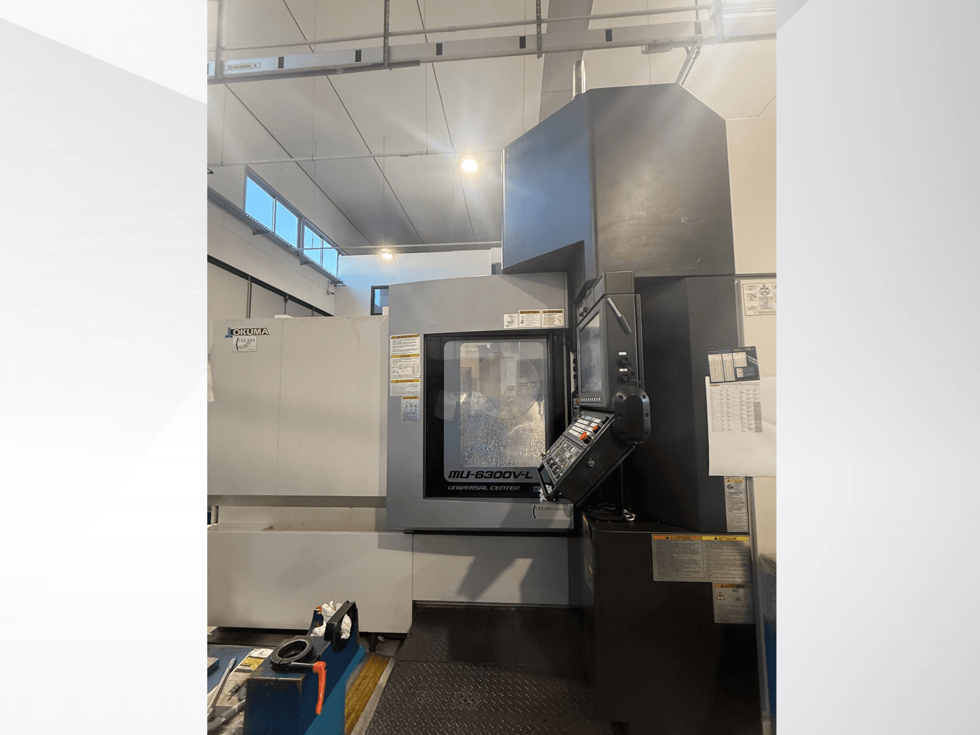 Okuma MU-6300V-L CNC staklės, žiūrint iš priekio, matomas valdymo skydelis ir saugos etiketės.