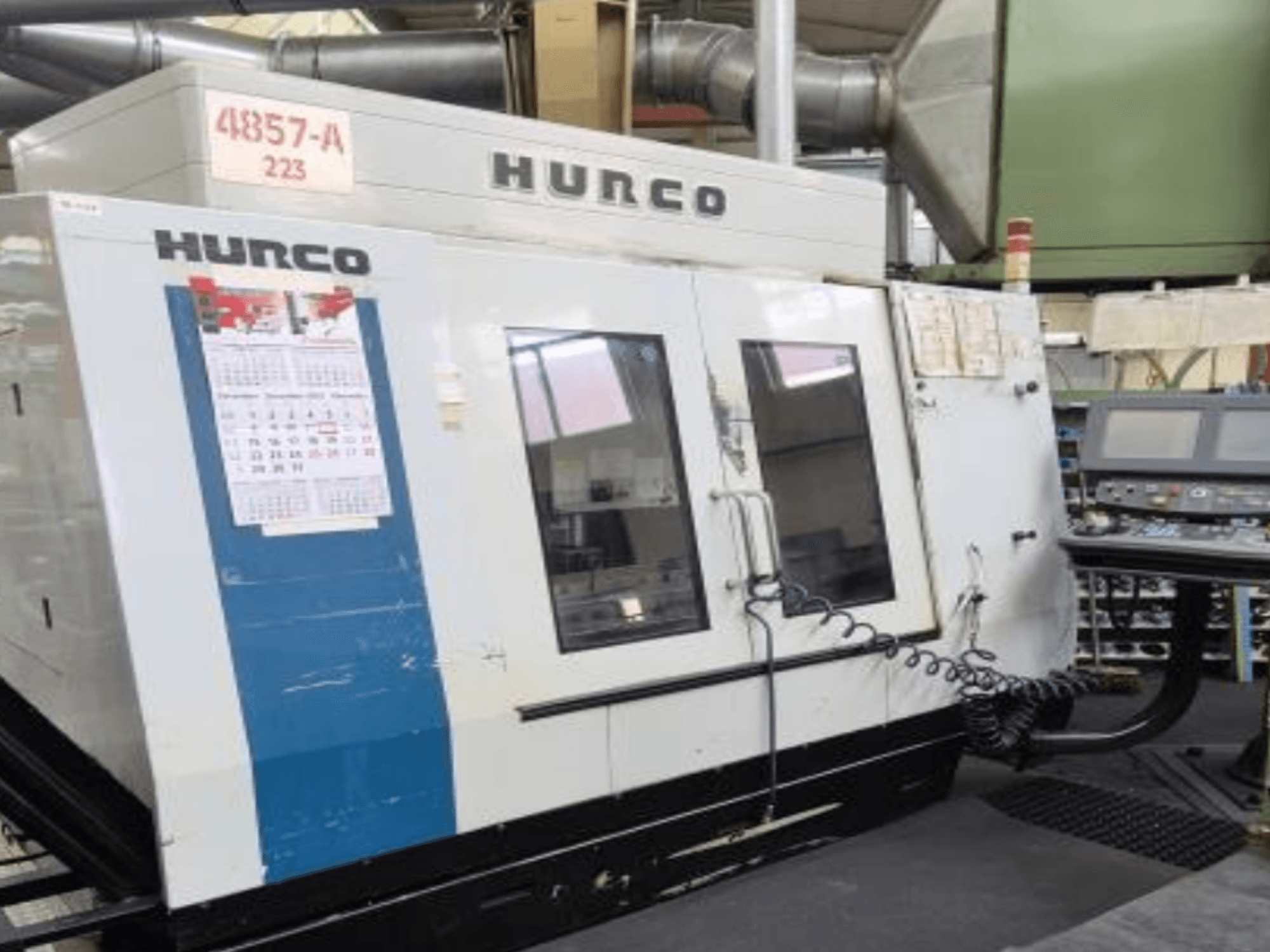 Vertikalaus apdirbimo centro "Hurco VMX 42" vaizdas iš priekio: valdymo skydelis, kalendorius ir metalinės išorės detalės.