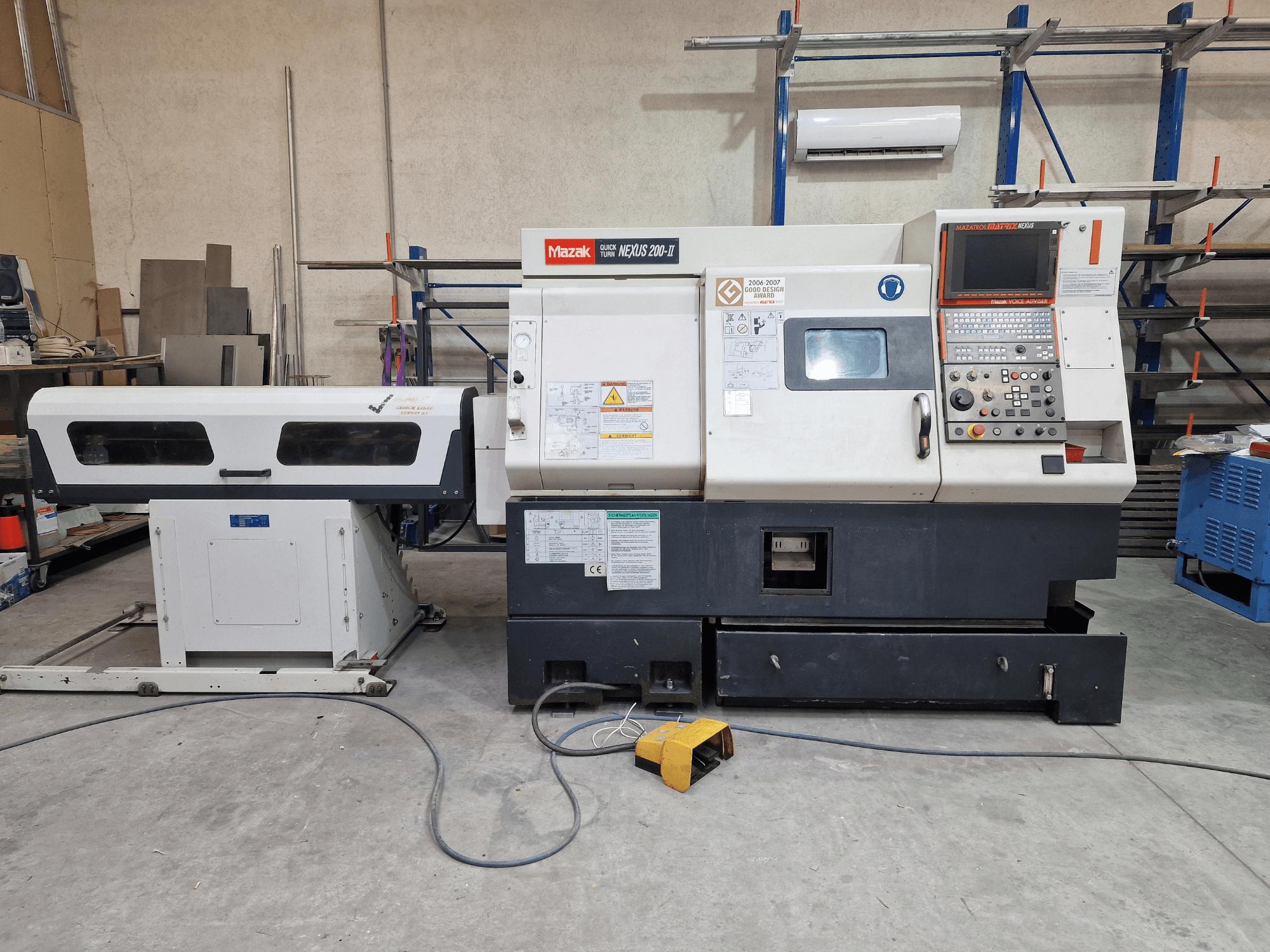 Mazak „QuickTurn Nexus 200“ horizontalus tekinimo staklės, vaizdas iš šono, kuriame matomas valdymo pultas, suklis ir drožlių surinkimo dėklas.