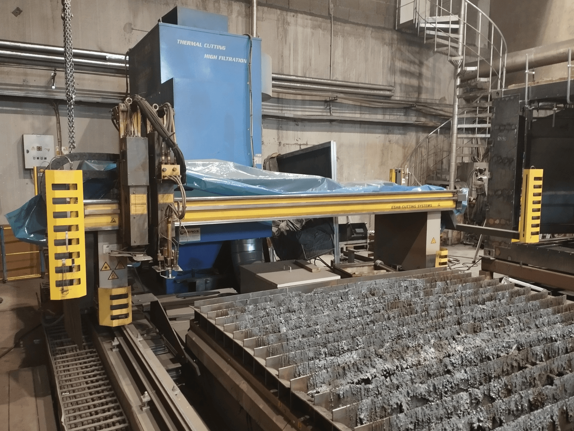 ESAB Combirex DX3500 oksiplazminio pjaustymo staklės, vaizdas iš priekio, su geltonais saugos elementais ir metalo pjaustymo stalu.