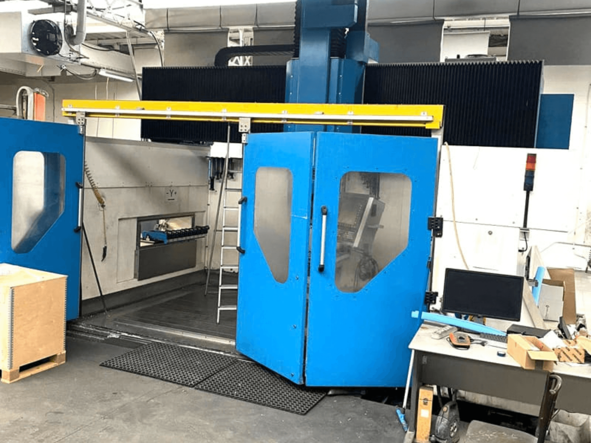 Vertikalaus apdirbimo centro „TECHMILL LABOR SHAPE 3220“ vaizdas iš priekio su atidarytomis mėlynomis durelėmis, pro kurias matoma vidinė darbo zona.